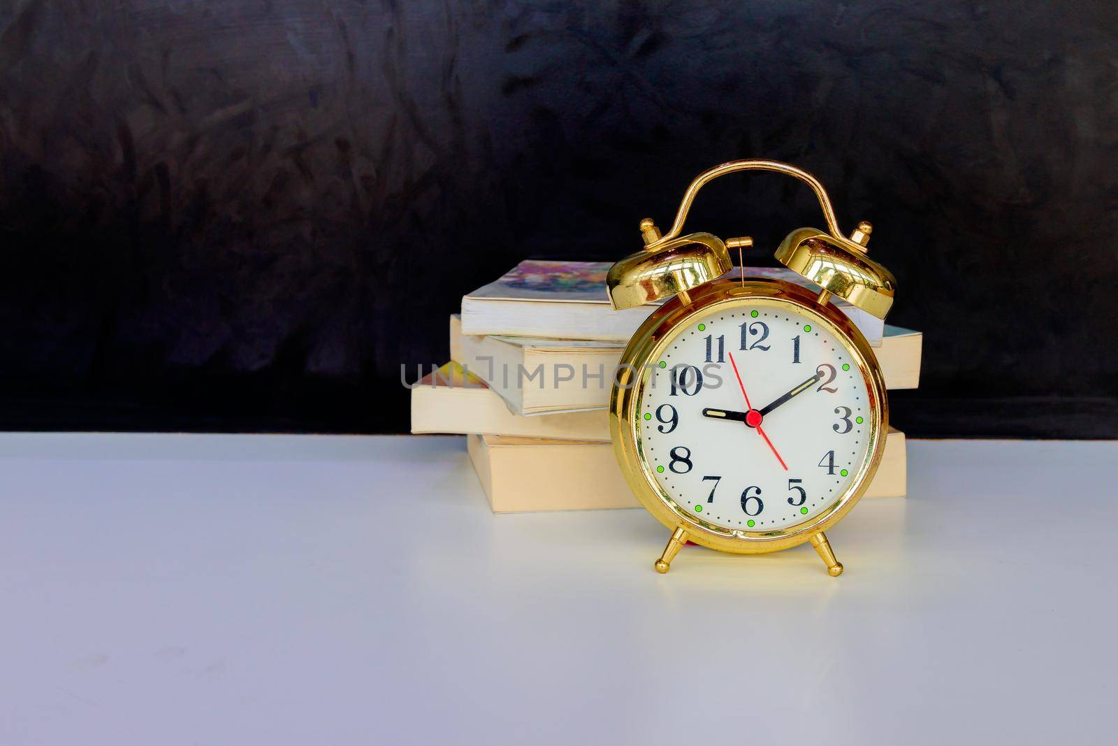 alarm clock old vintage gold and book over white on black background. with copy space add text