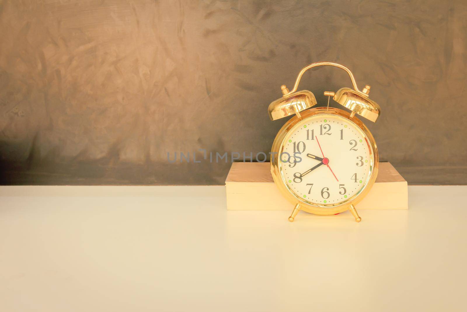 alarm clock old vintage gold and book over white on black background. with copy space add text. color cinematic Vintage style tone