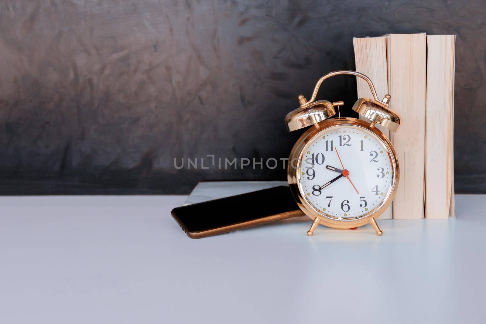 alarm clock old vintage gold and mobile phone, book over white on black background. with copy space add text