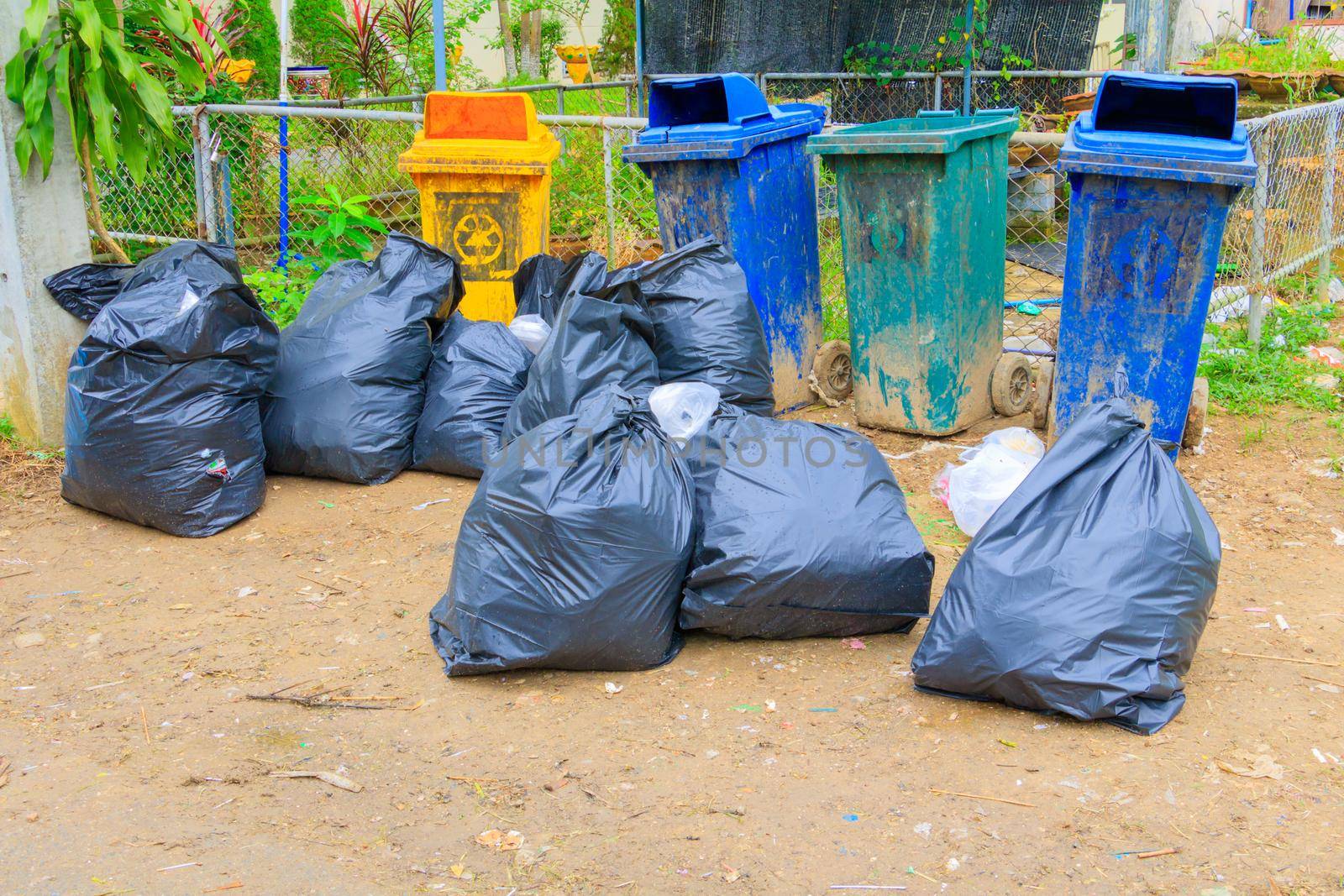 pile black garbage bag plastic and four dustbin dirty roadside in the city