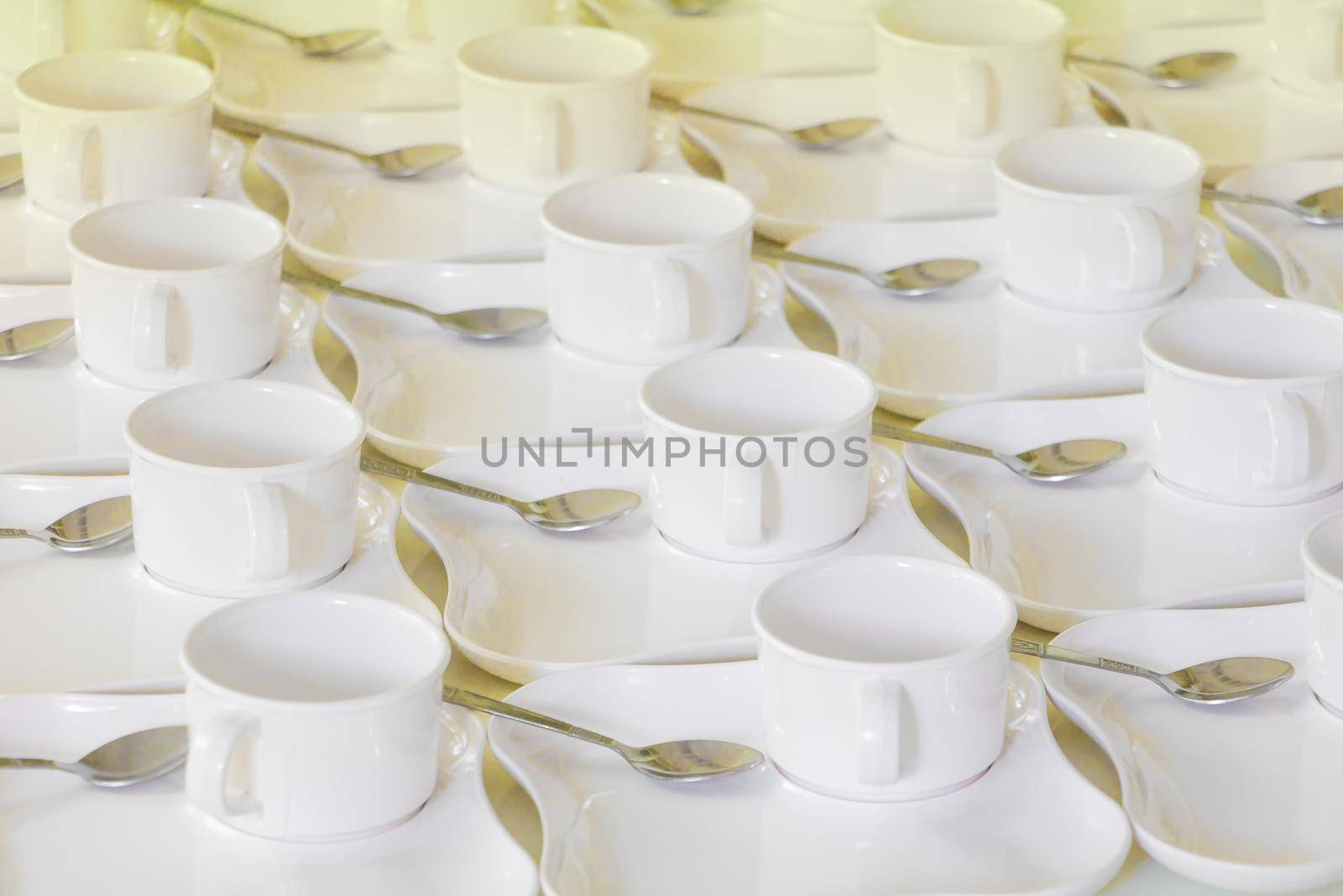 white coffee cup row with saucer and spoon on table by pramot