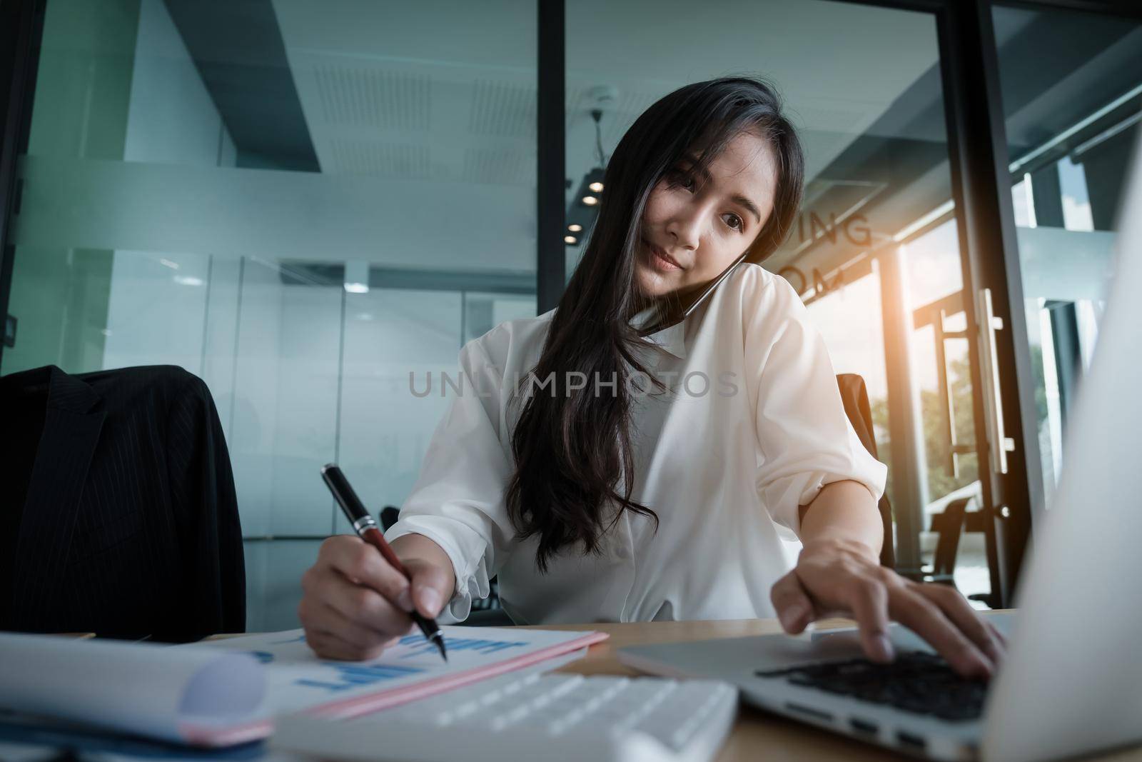 Business woman hand holding pen and pointing at financial paperwork with financial network diagram