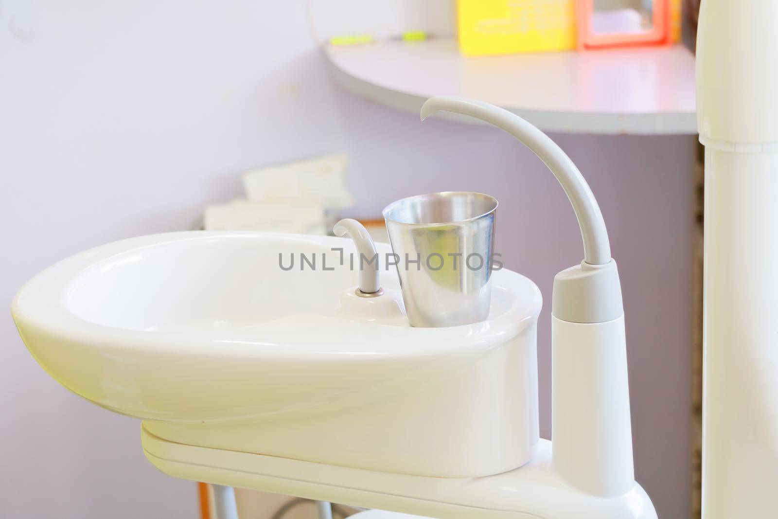 glass chromium on Sink medical equipment dentist Close up, ceramic spittoon and water filler in Clinic by pramot