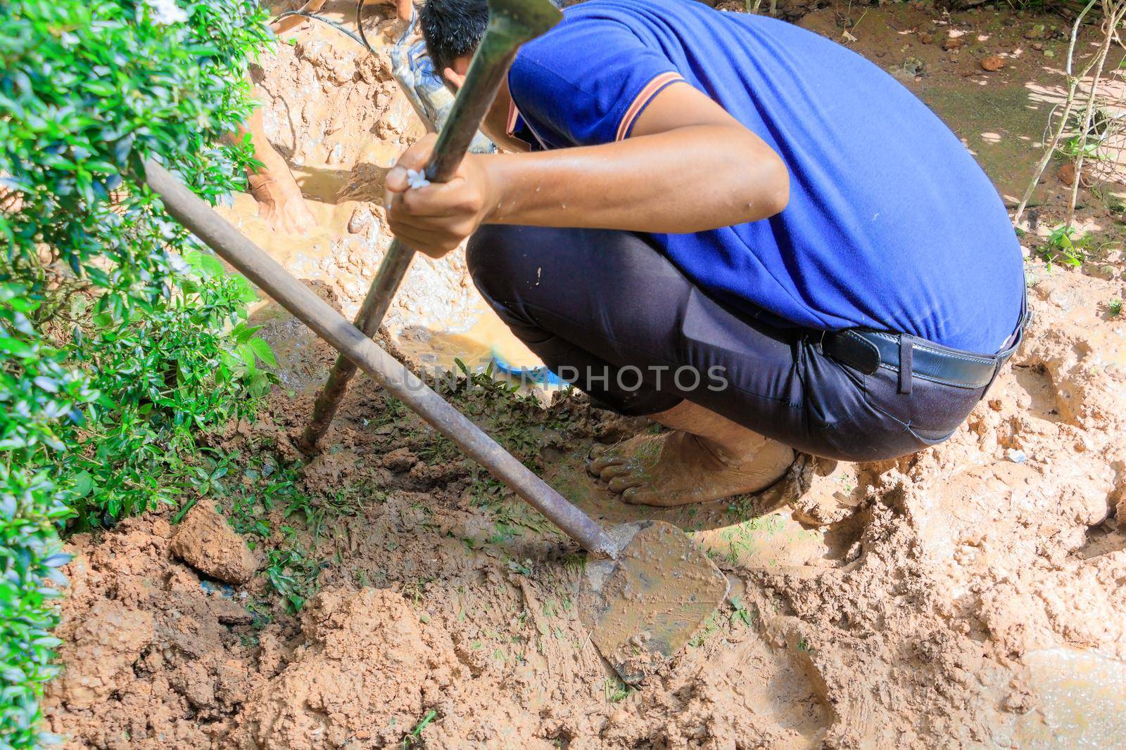 male plumber are repair broken pipe in hole with plumbing water flow outdoor and sunlight with copy space add text