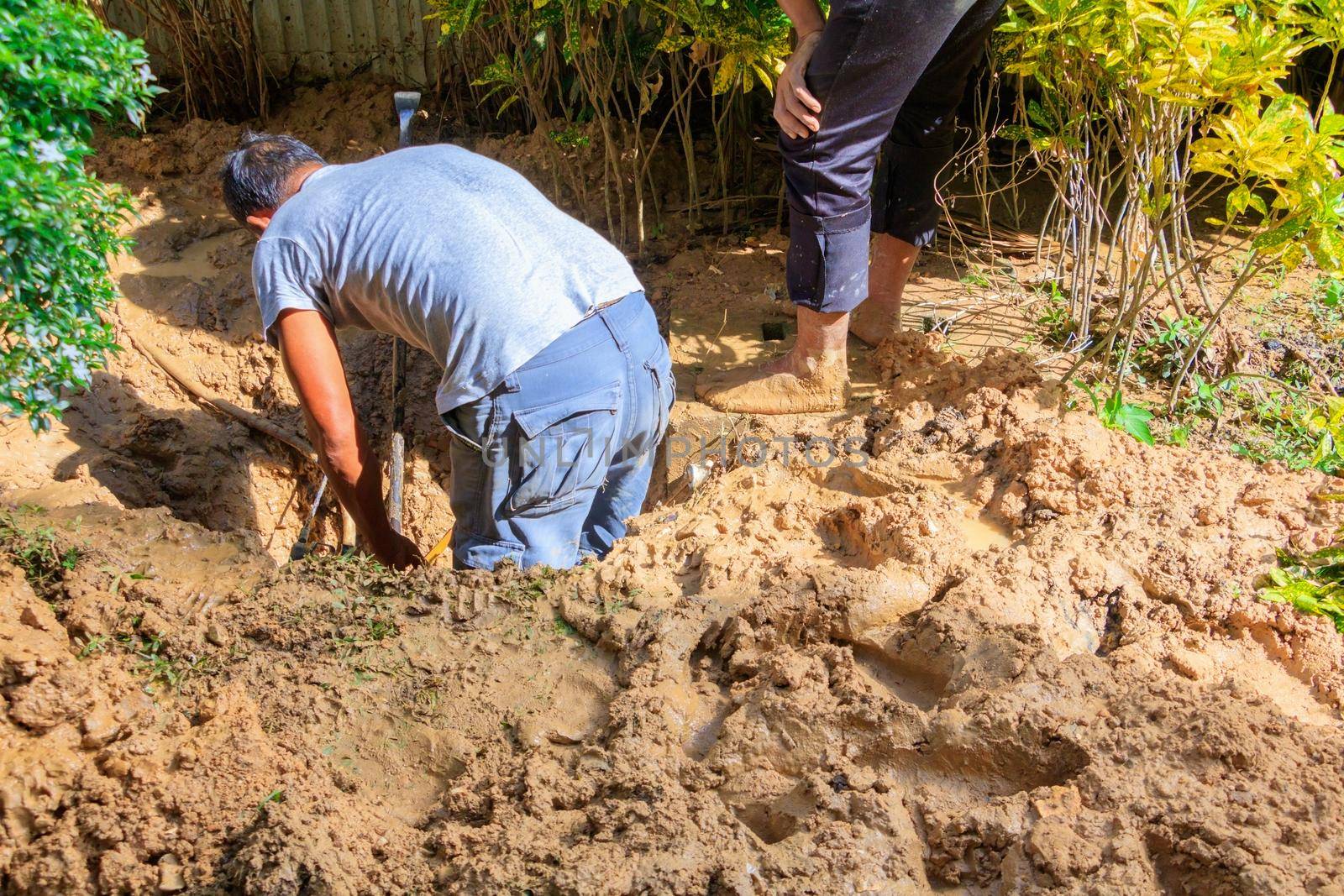 male plumber are repair broken pipe in hole with plumbing water flow outdoor and sunlight with copy space add text