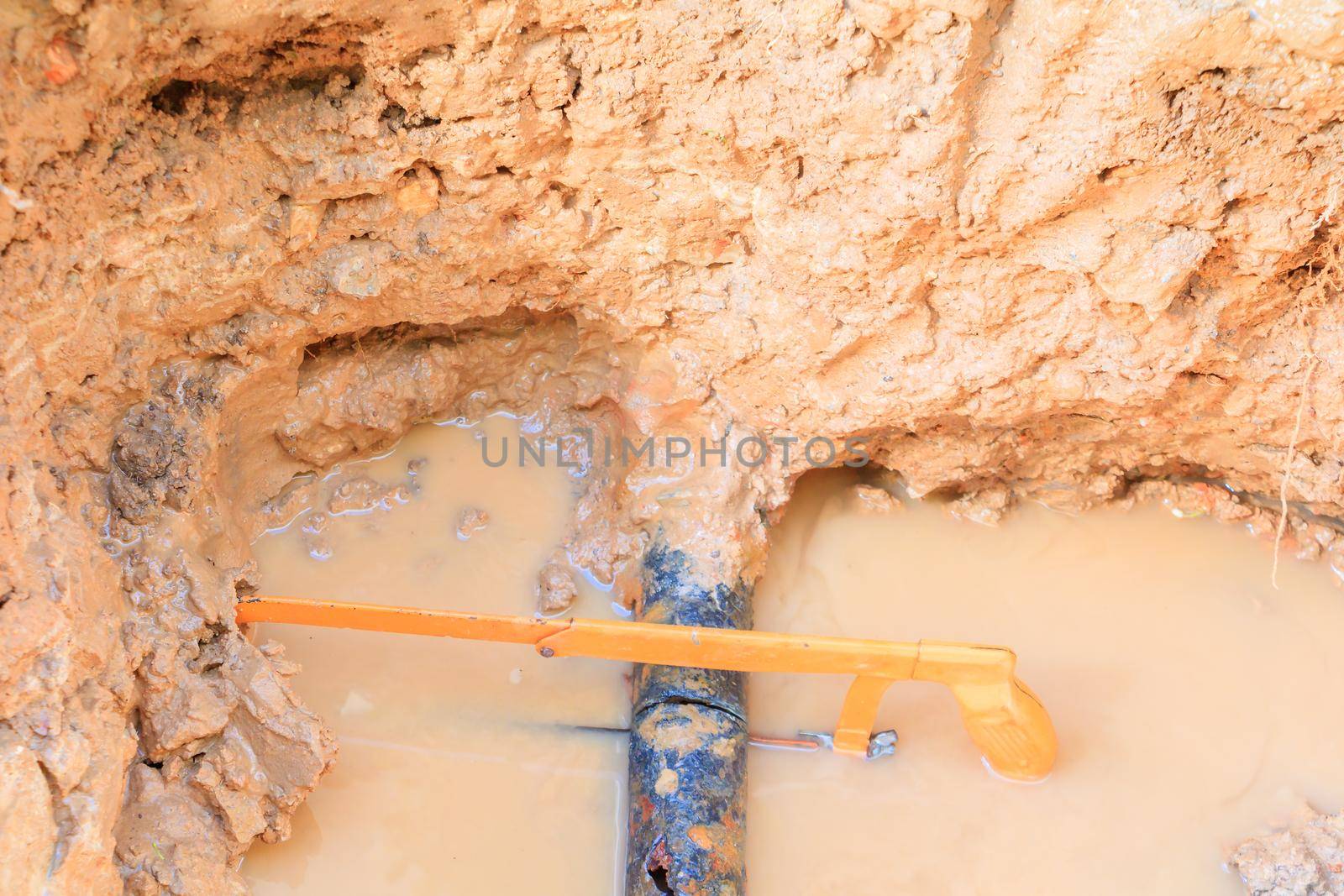 repair broken pipe in hole with plumbing water flow underground outdoor and sunlight with copy space add text