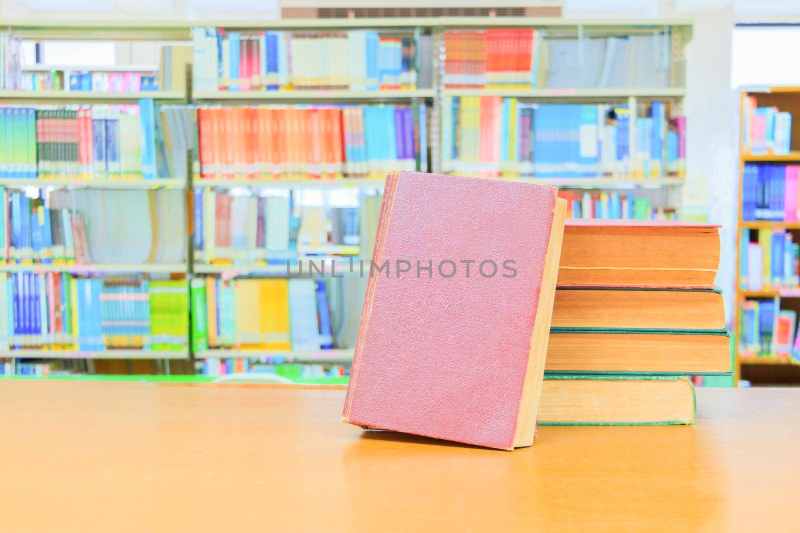 old book red - green. heap are interior library school on wooden table and blurry bookshelves background. education learning concept with copy space add text by pramot