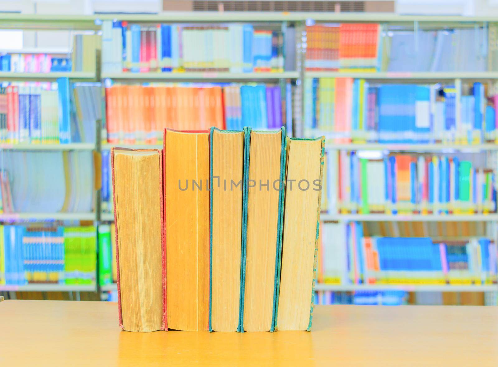 old book red - green. heap are interior library school on wooden table and blurry bookshelves background. education learning concept with copy space add text