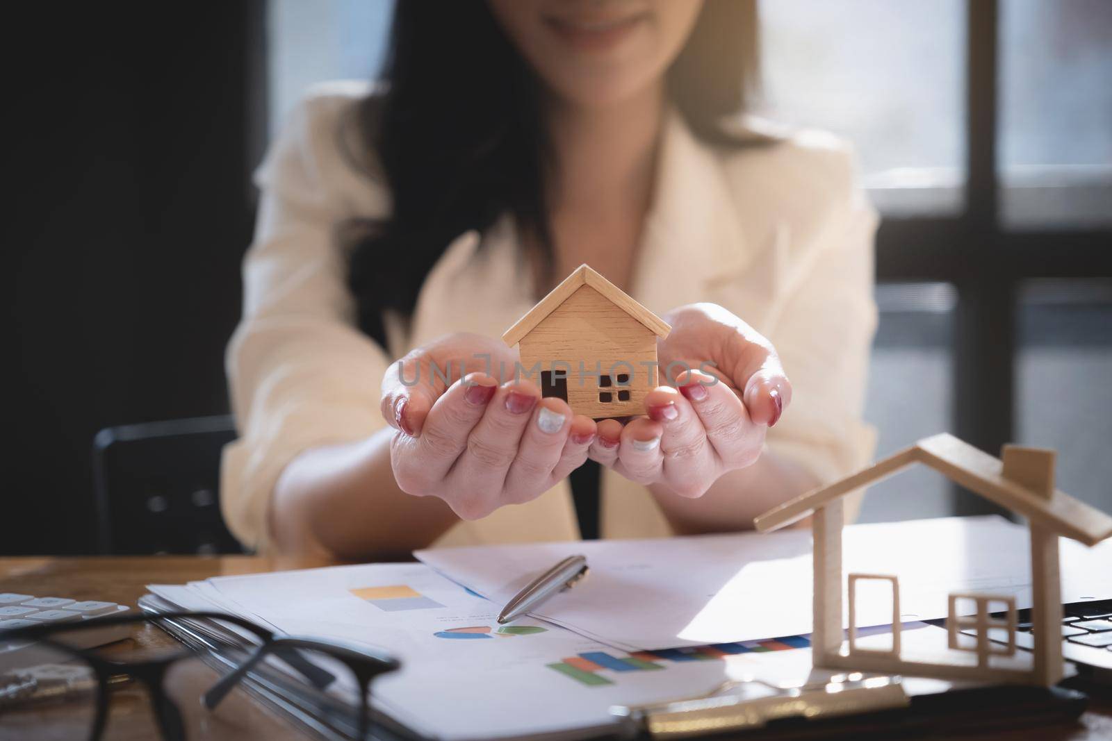 Insurance agent protecting wooden model of the house. Property insurance concept