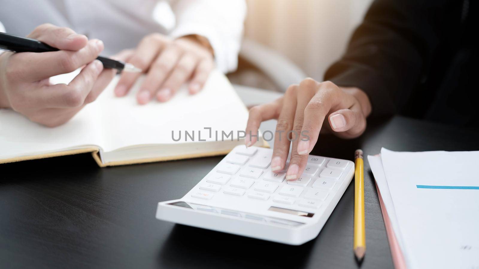 Close up Businessman and partner using calculator and laptop for calaulating finance, tax, accounting, statistics and analytic research concept by wichayada