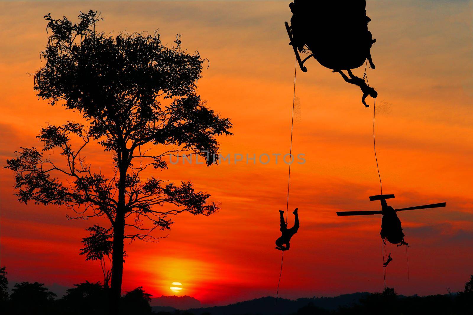 Silhouette Soldiers rappel down to attack from helicopter with sunset and copy space add text ( Concept stop hostilities To peace) by pramot