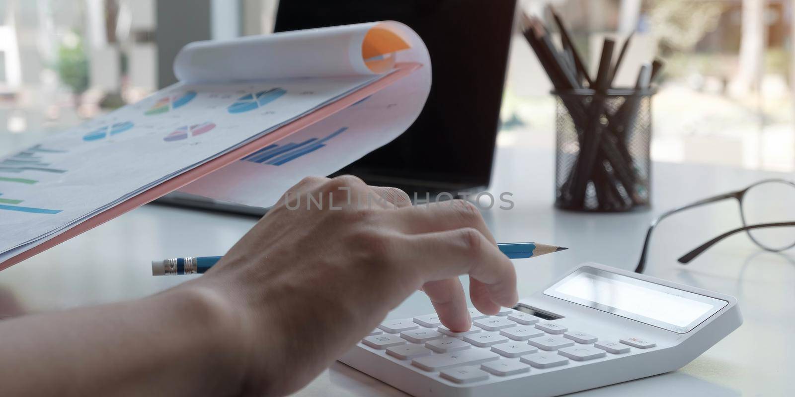 Close up Businessman using calculator and laptop for do math finance on wooden desk in office and business working background, tax, accounting, statistics and analytic research concept.