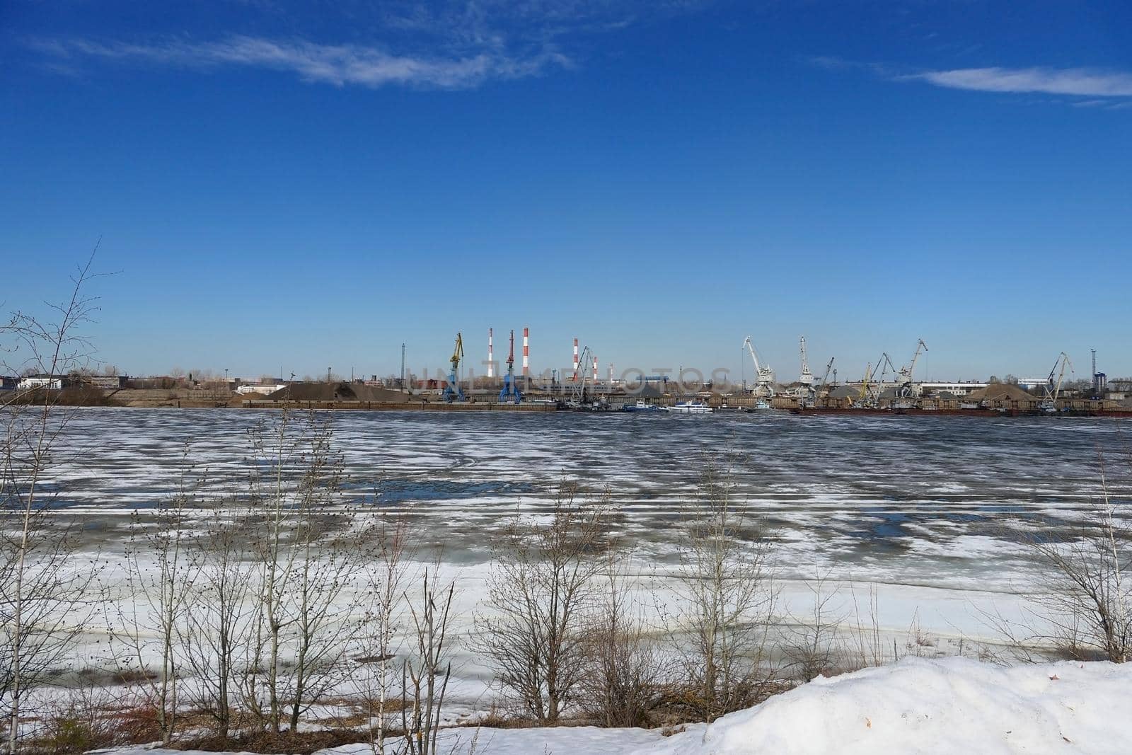 Spring ice on the river. Plant by the river and sand mining. High quality photo