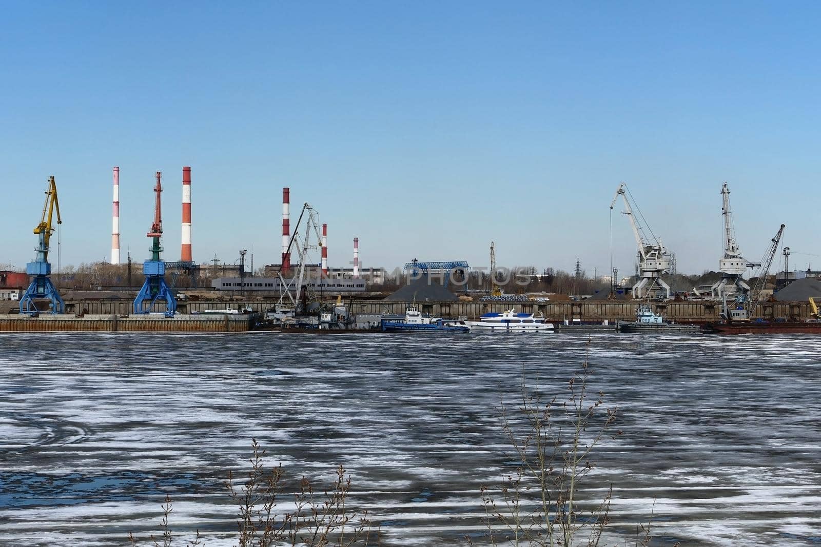 Spring ice on the river. Plant by the river and sand mining. High quality photo