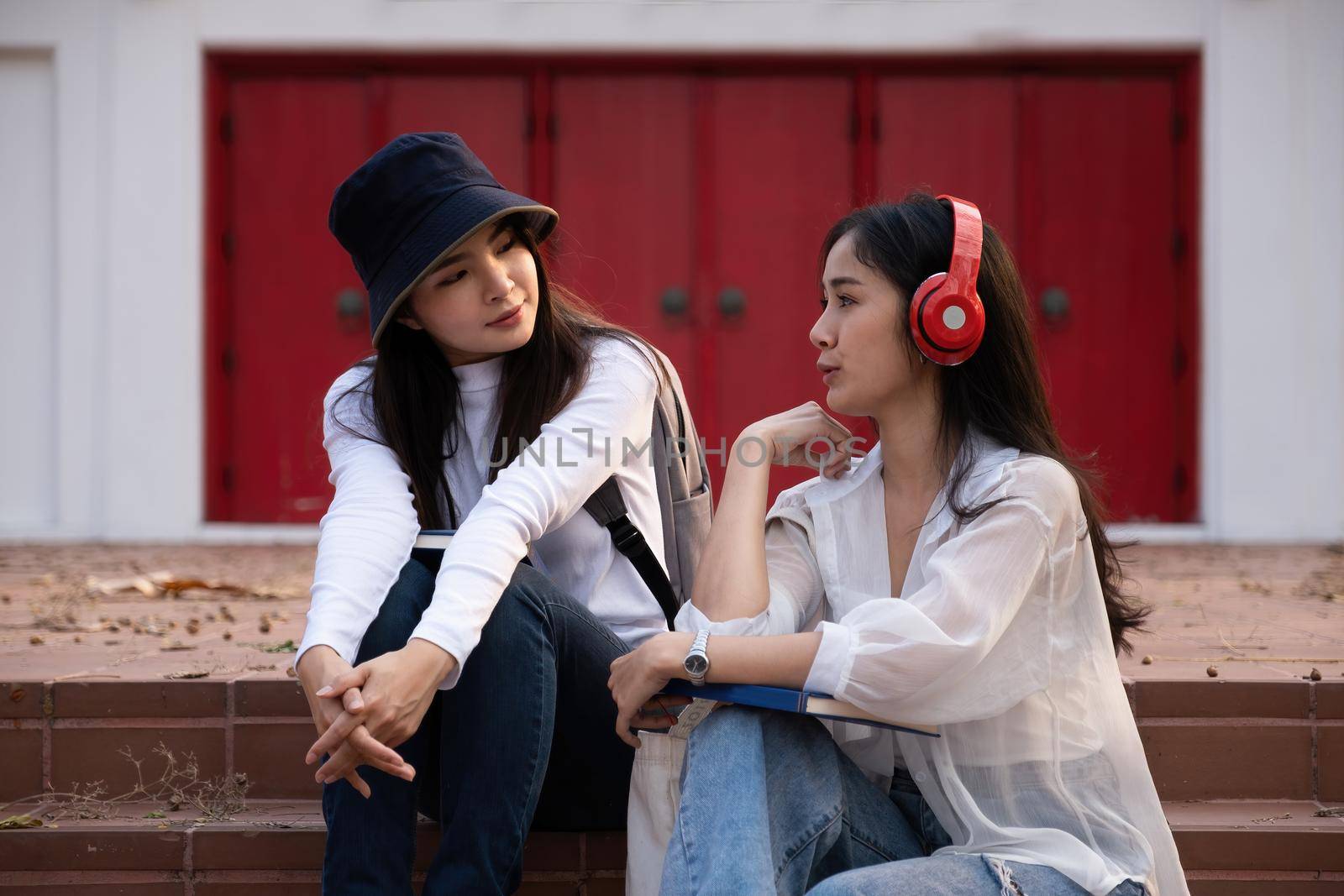 Asian woman traveler with backpack talking about history this place and sitting in stair, travel holiday relaxation concept