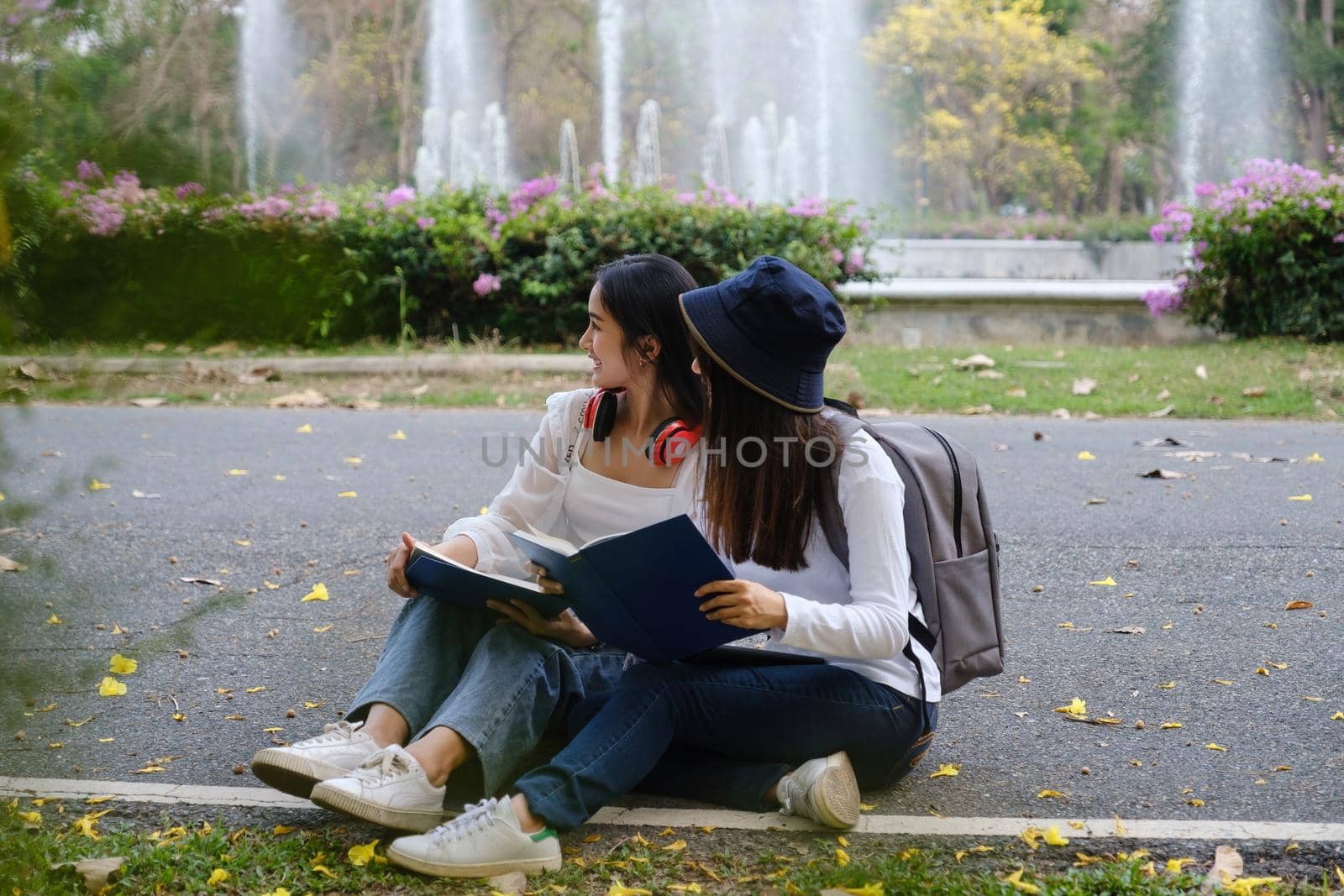 Two students are sitting in university during reading a book and communication. Study, education, university, college, graduate concept