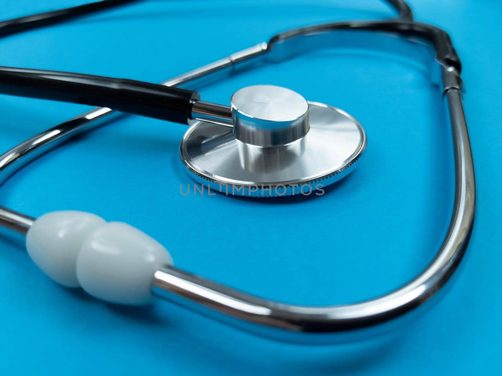 Black stethoscope on a blue background. Stock photo.