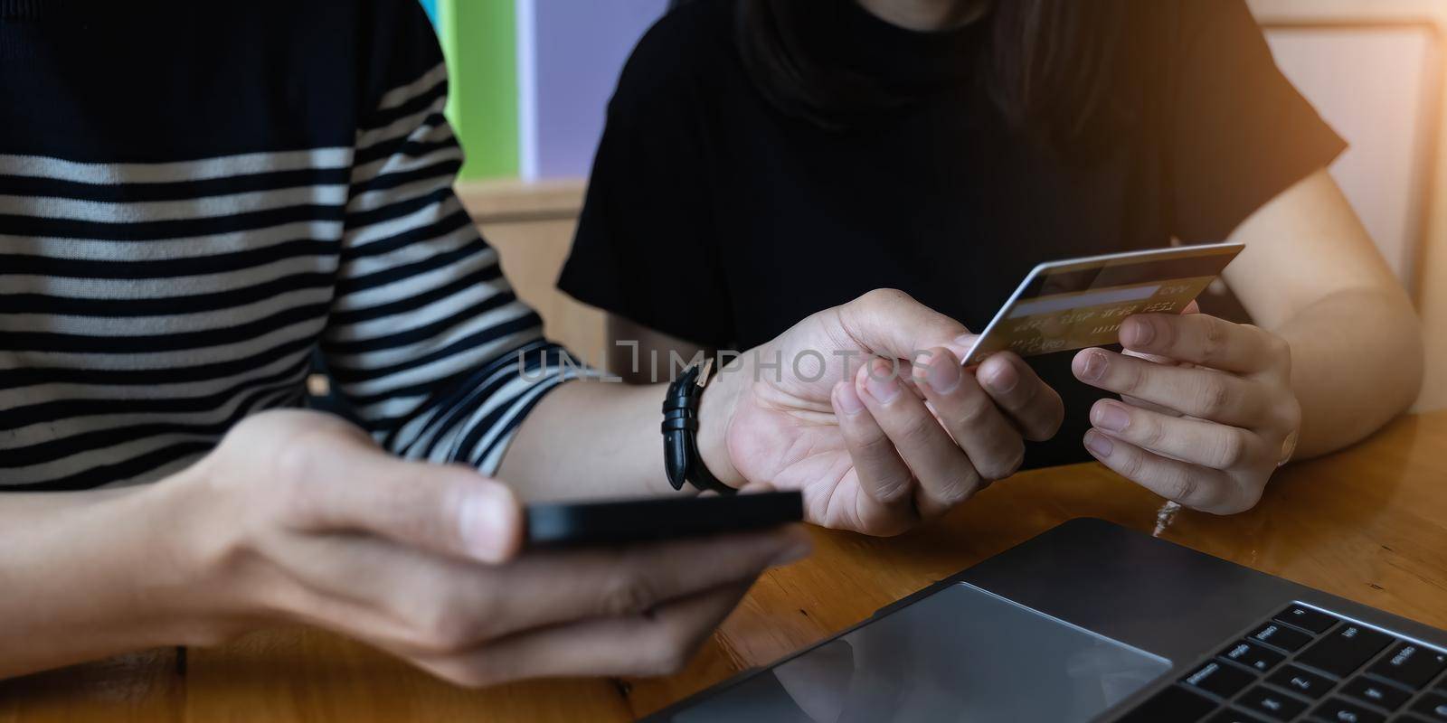 Young couple holding credit card and using phone. Online shopping, e-commerce, internet banking, spending money