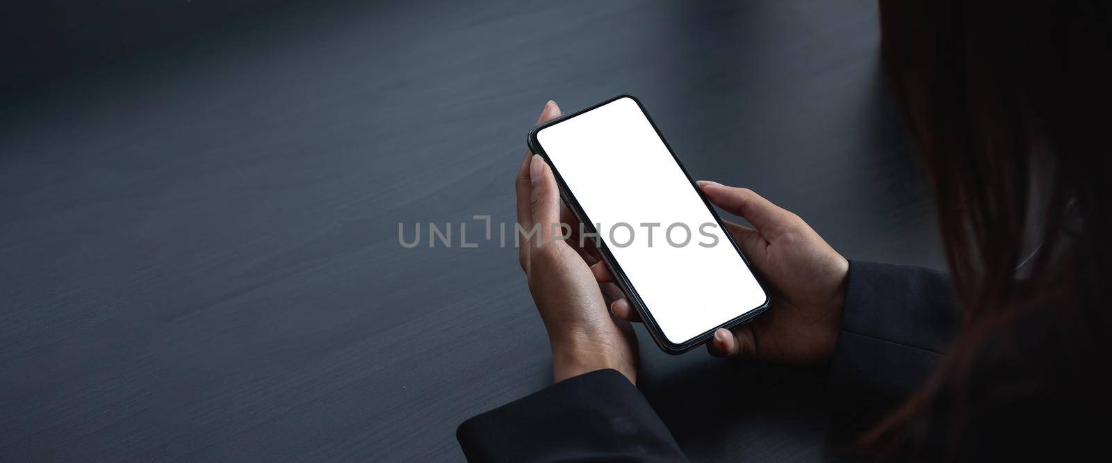 cell phone blank white screen mockup. woman hand holding texting using mobile on desk at office.background empty space for advertise. by nateemee