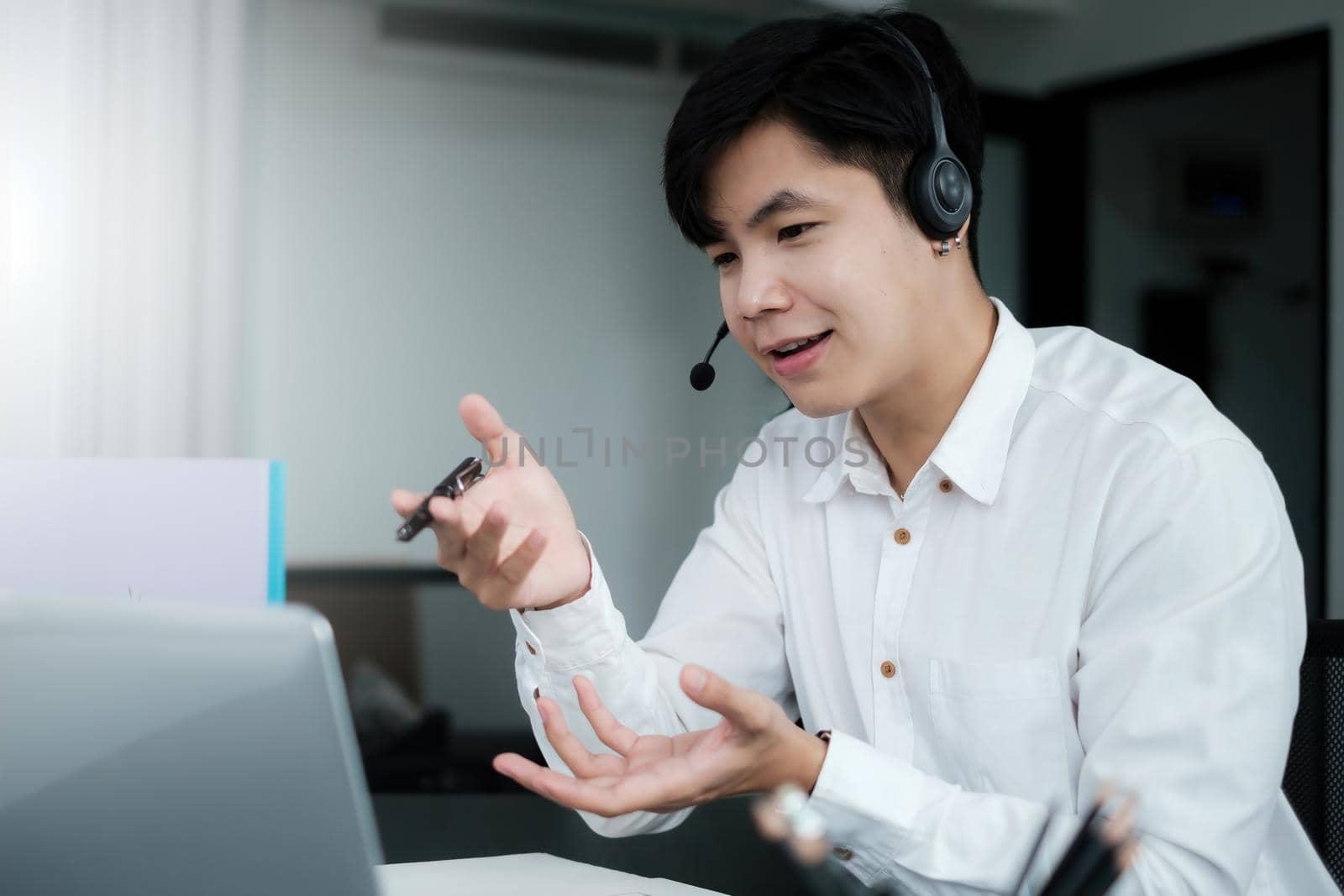 Businessman discuss with partners by video call. Male technical support agent trying to explain something to a client while working on laptop at call center. by itchaznong