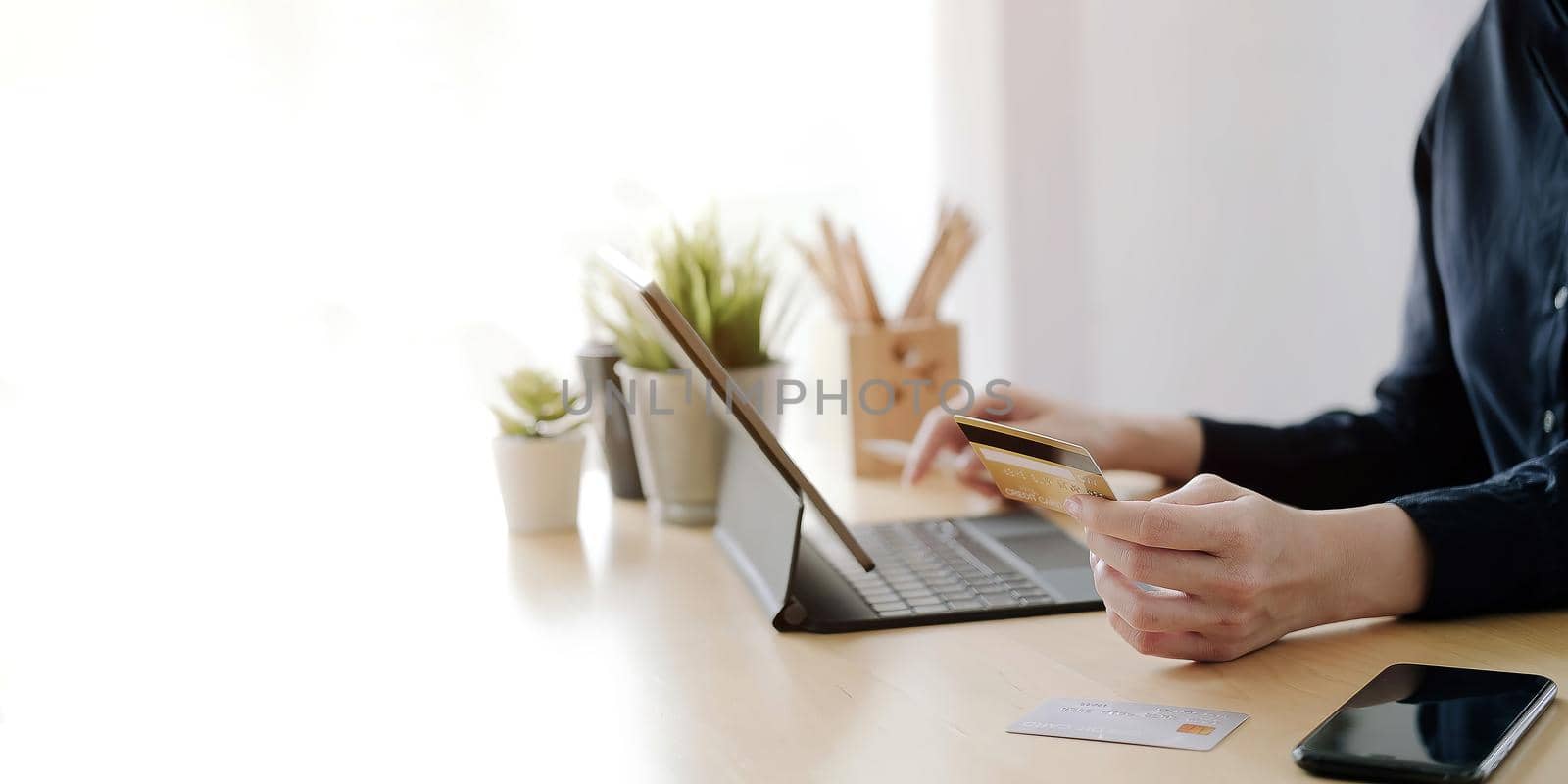 Close up hand of woman holding credit card and using laptop computer at home. Online shopping concept.