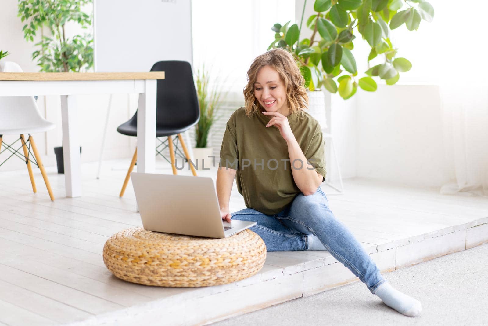 Woman using laptop computer while sitting floor at home interior. Freelance female working from home Distance learning student relaxing and watch lessons on video conference .
