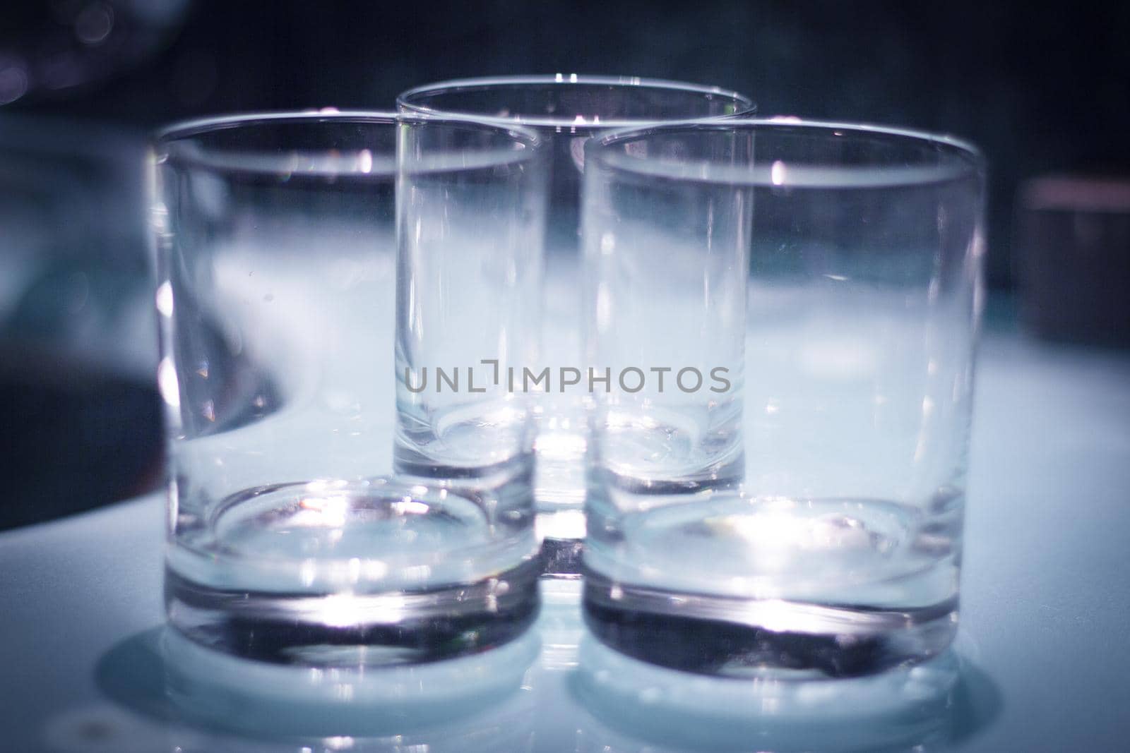 Three empty crystal glasses on dark background. No people