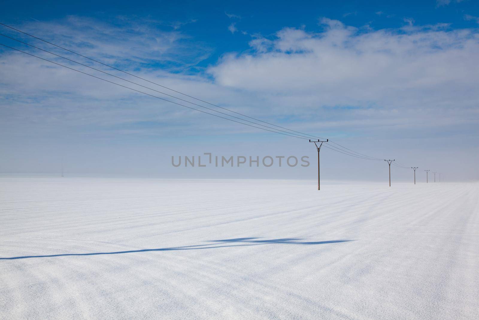 Winter landscape with power line columns  a snow covered field.