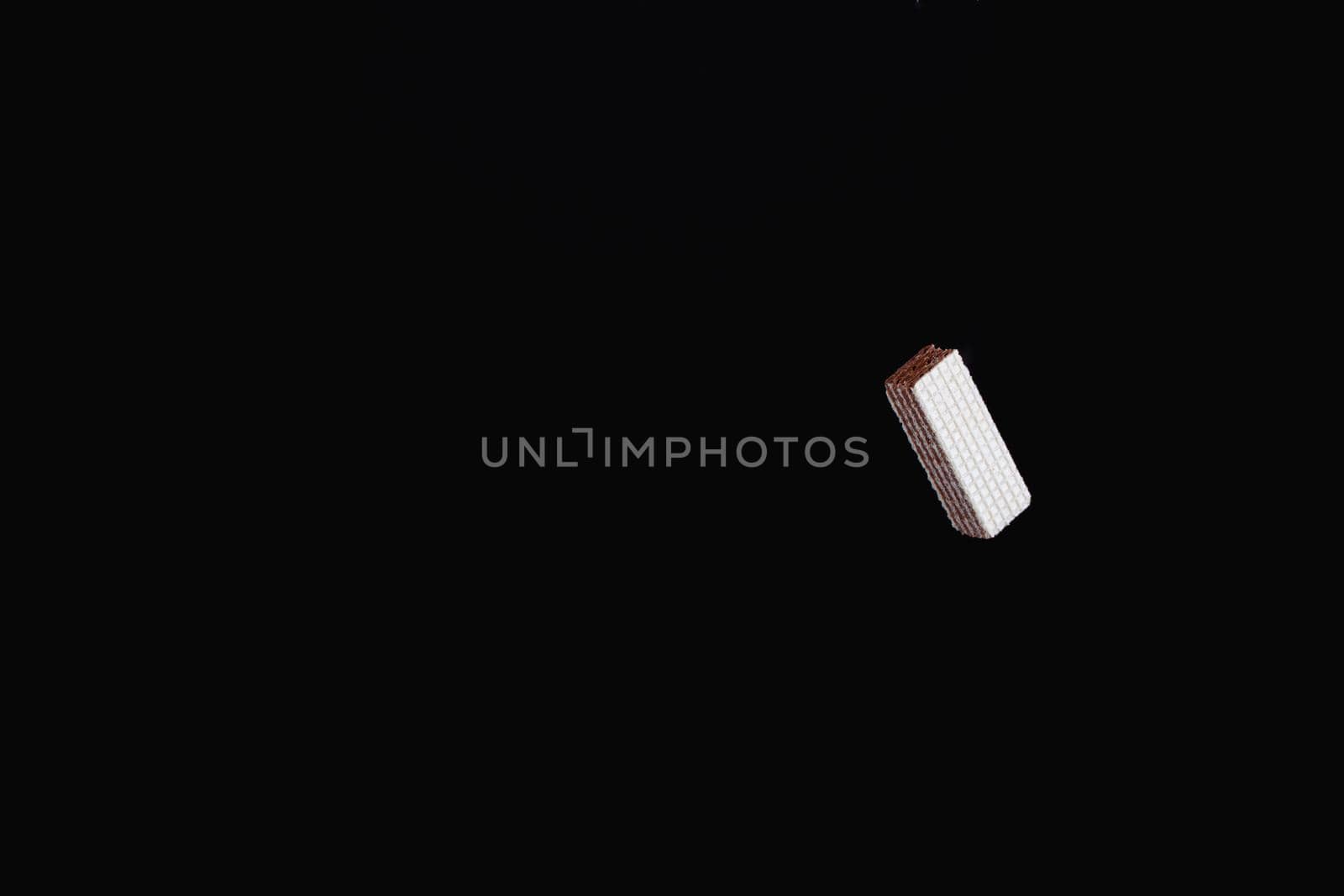 One levitating chocolate wafer on a black background