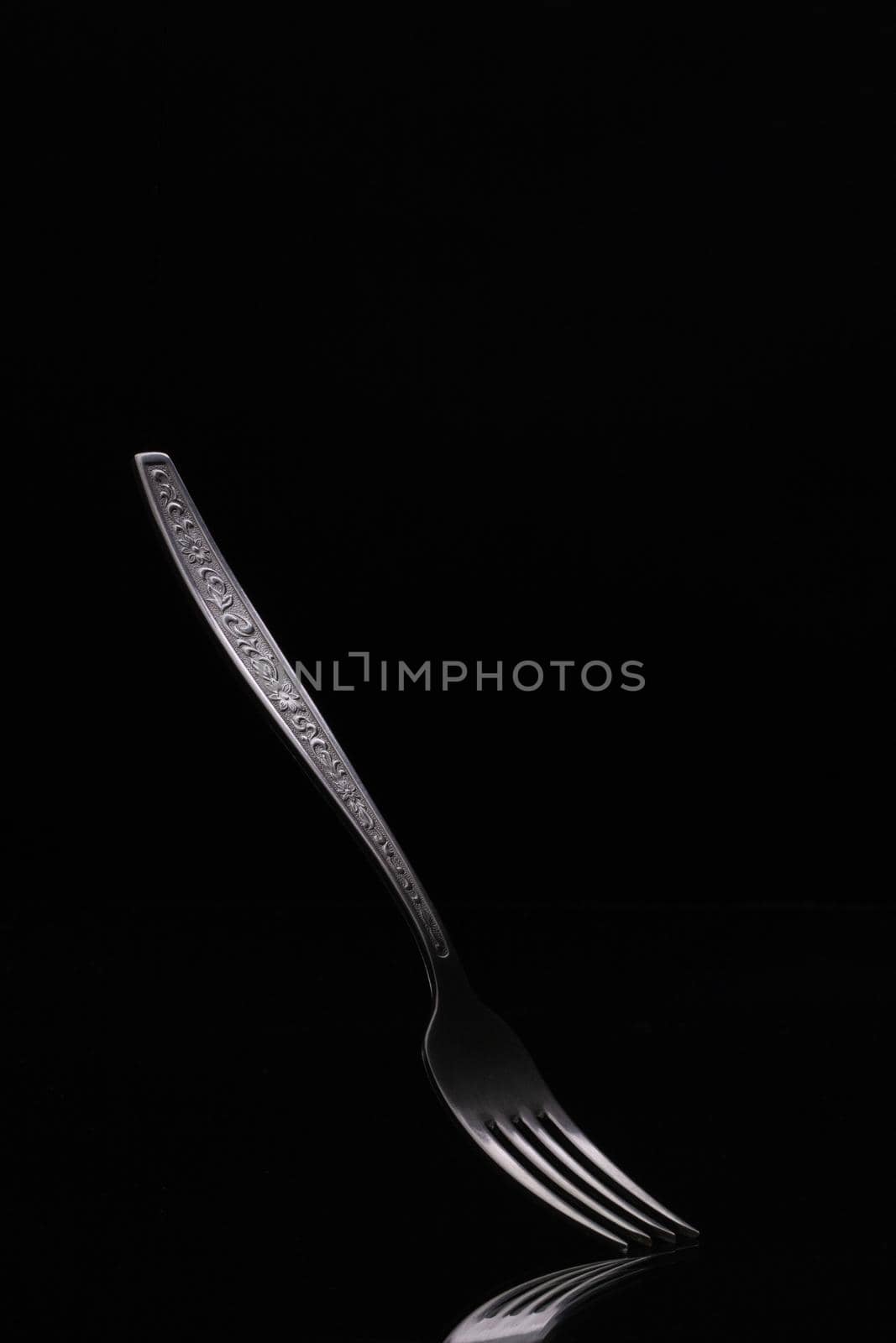 Old steel fork on black background. Metal fork on dark background close up.