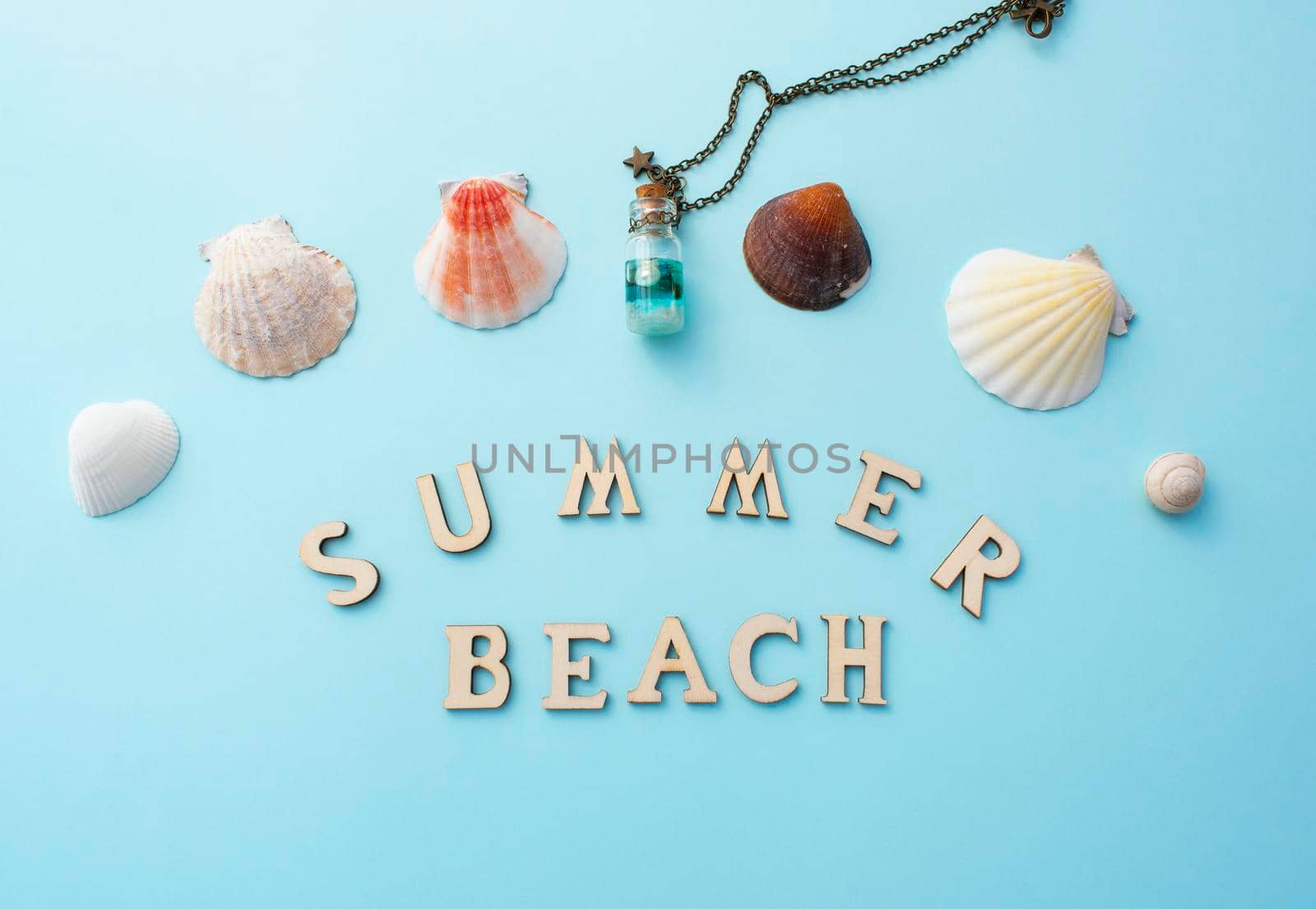 Summer beach wooden inscription. White shells and bottle decoration on light blue background.