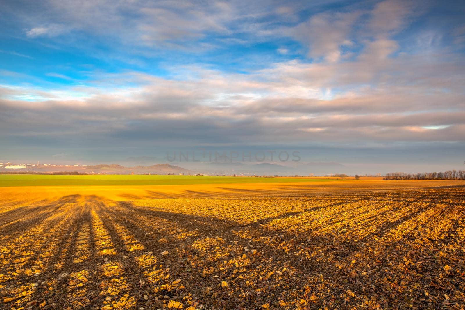 Autumn morning landscape over the city of Louny. Autumn plowed field at amazing sunrise. Czech Republic