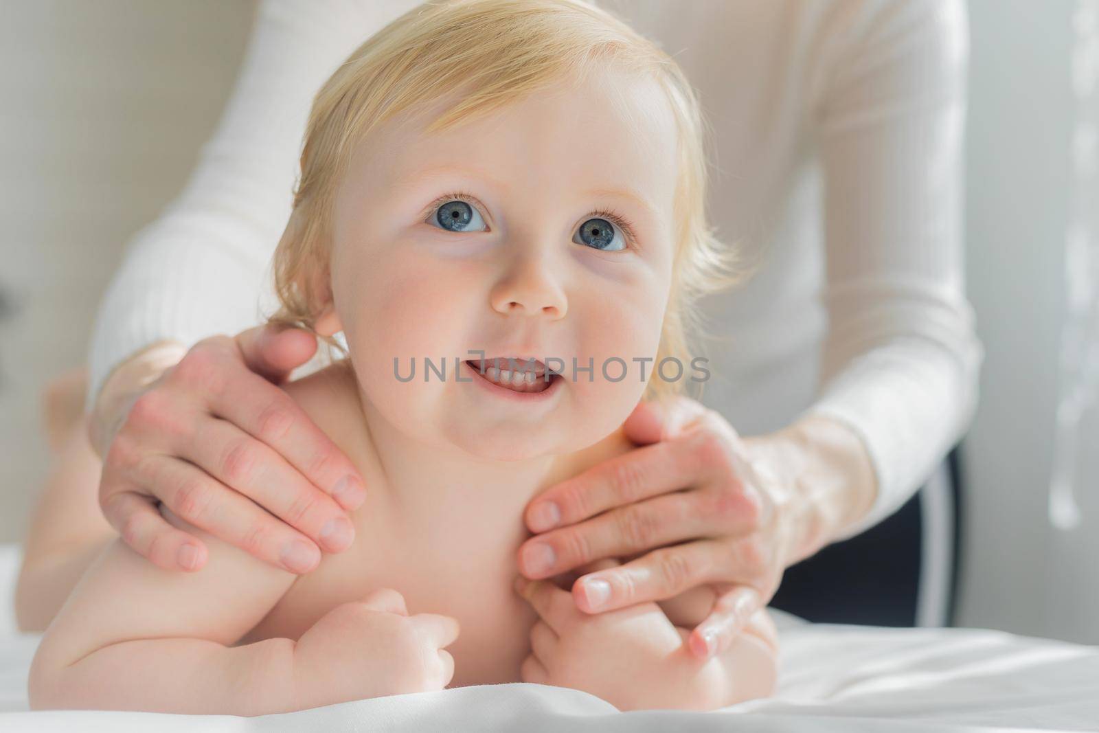 Mom gives her baby a shoulder and back massage. Close-up. A satisfied baby lies on the massage table.