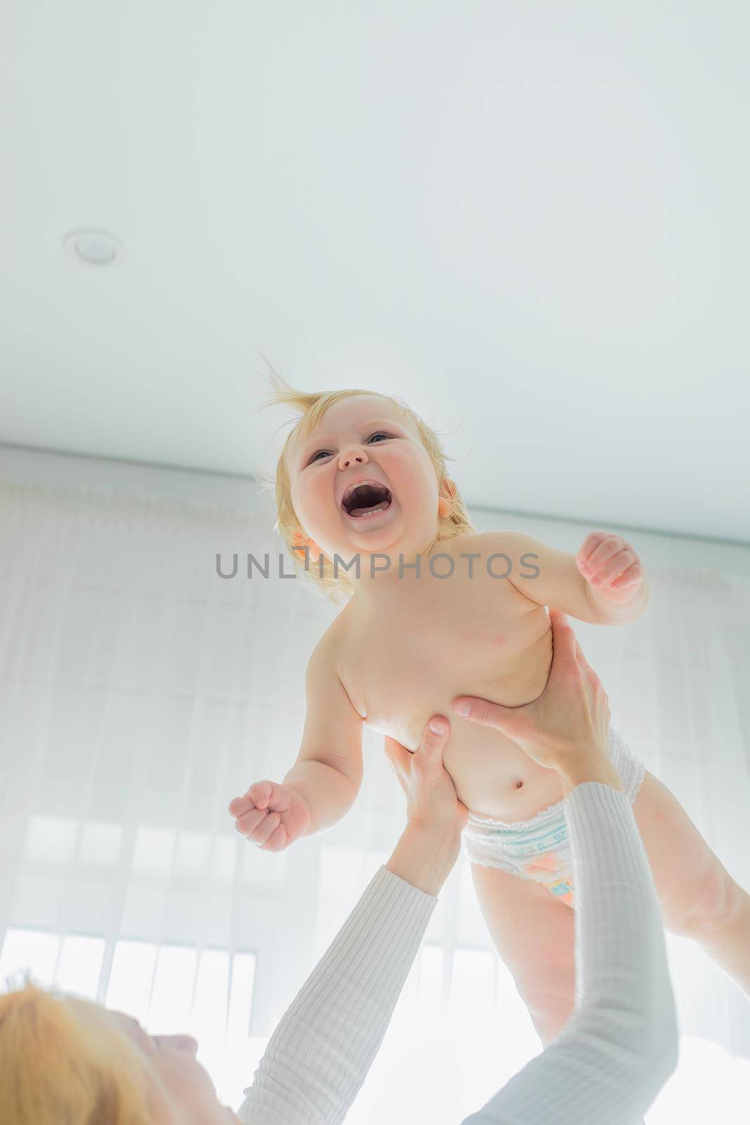 Mom, entertaining the baby, throws him up, rejoicing and having fun by Yurich32