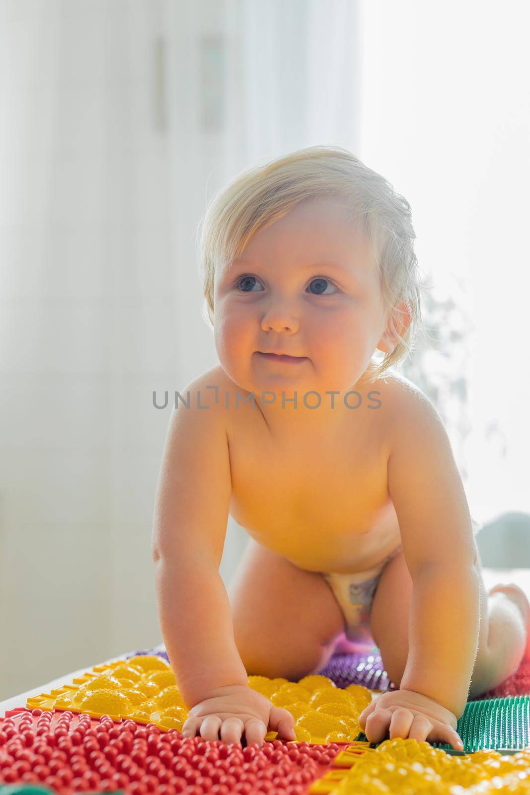 The kid walks barefoot on multi-colored massage rugs. Foot massage