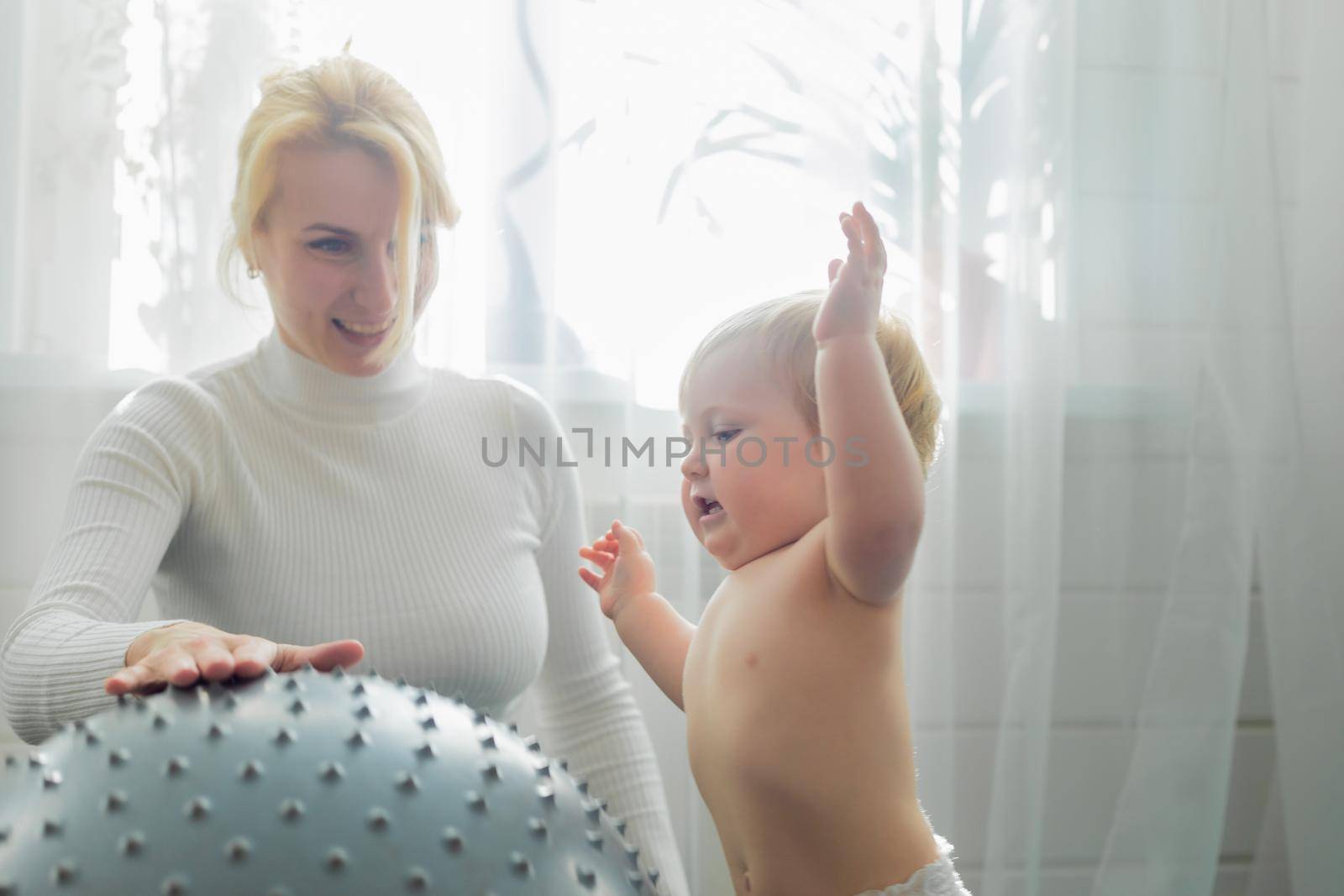 Mom is engaged in gymnastics with the baby on an inflatable ball. Fitball, gymnastics for a child.