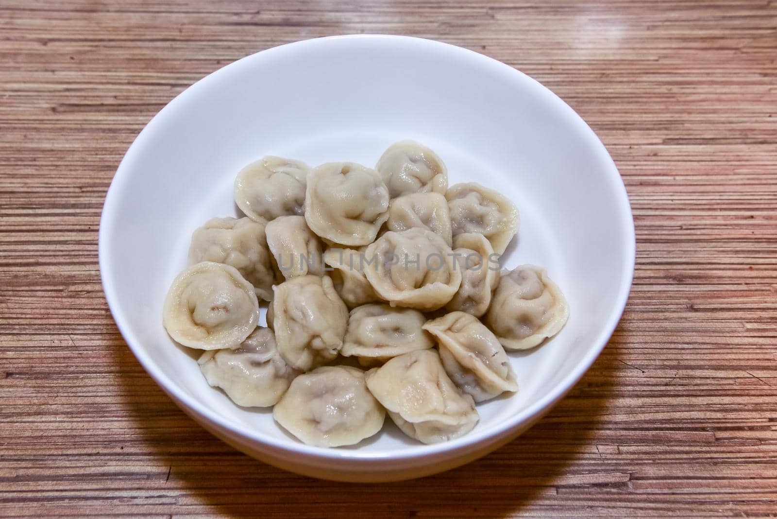 plate with homemade Russian dumplings on a wooden table.