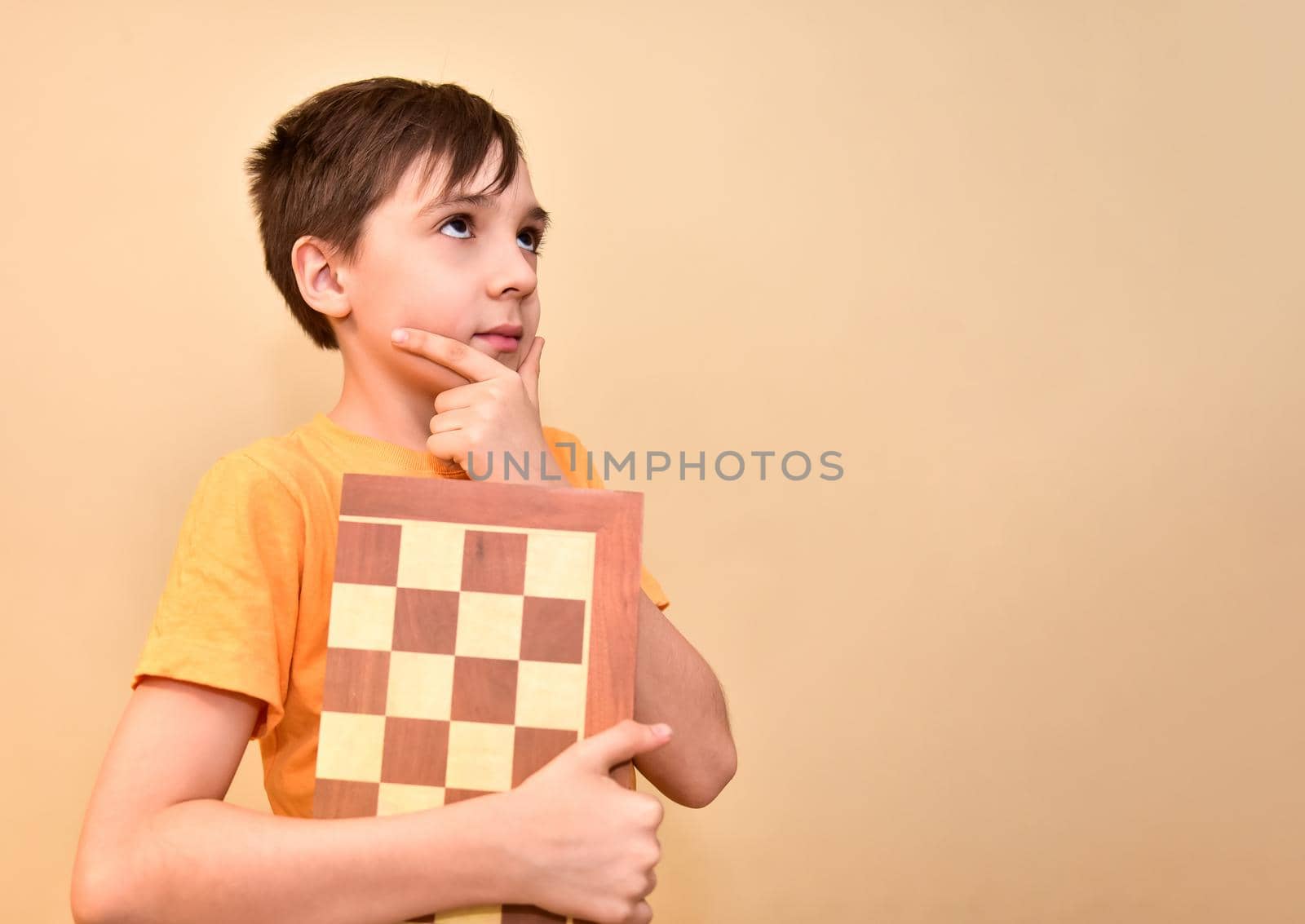 boy holds a chessboard in his hands and dreams and thinks about the game. free space for text by karpovkottt