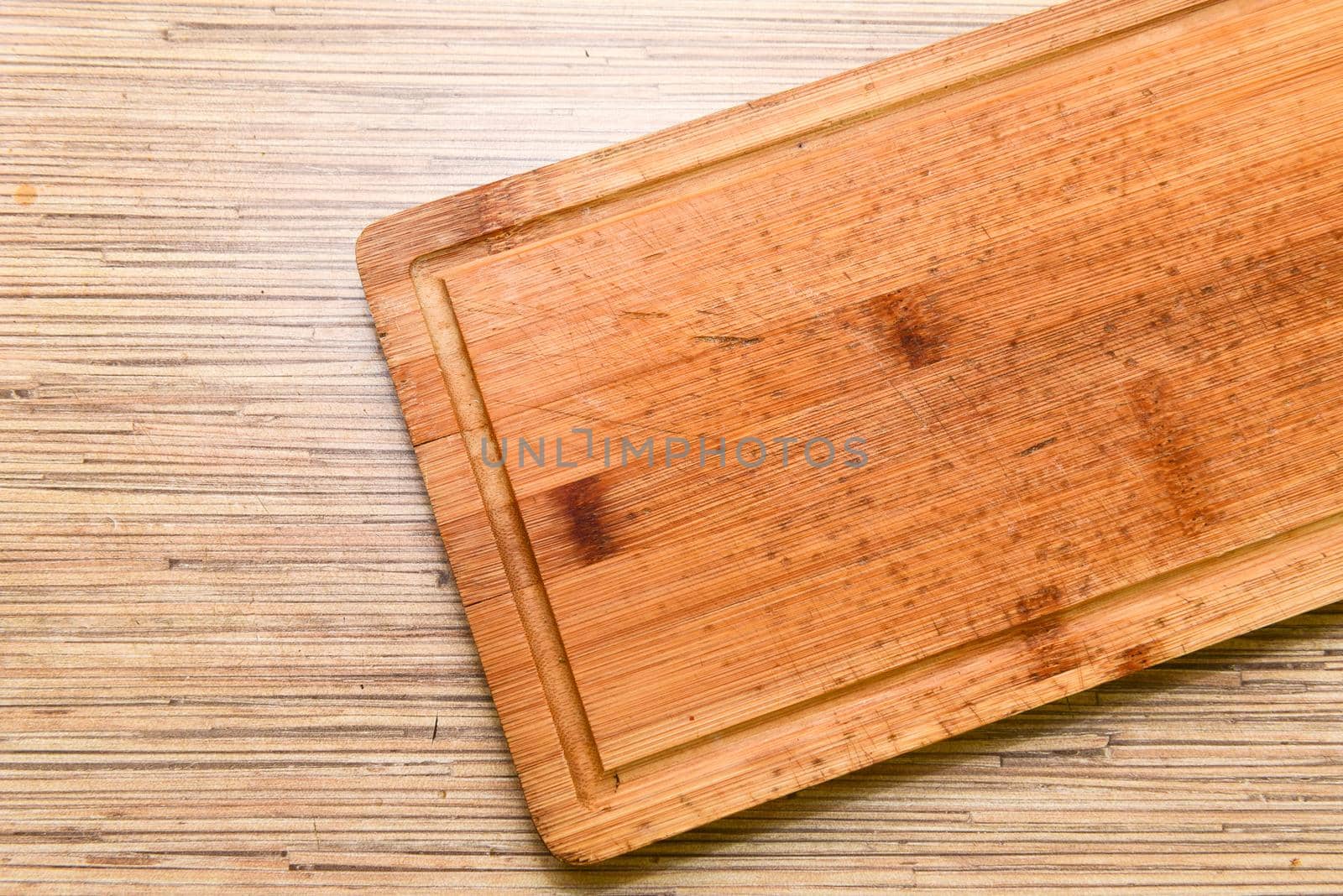 Old chopping board on wooden background top view.