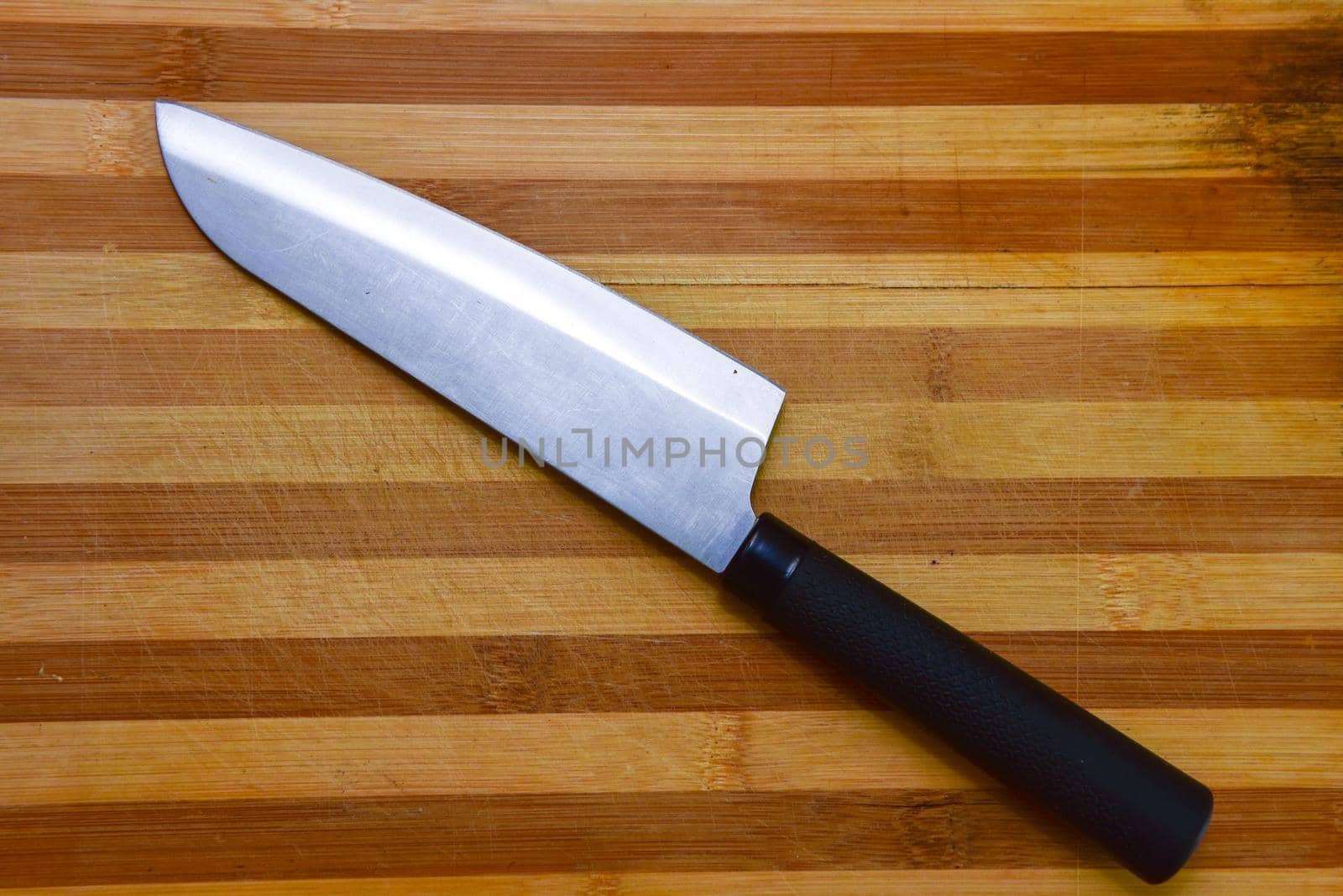 Cutting board and a kitchen knife on wooden background. Top view.