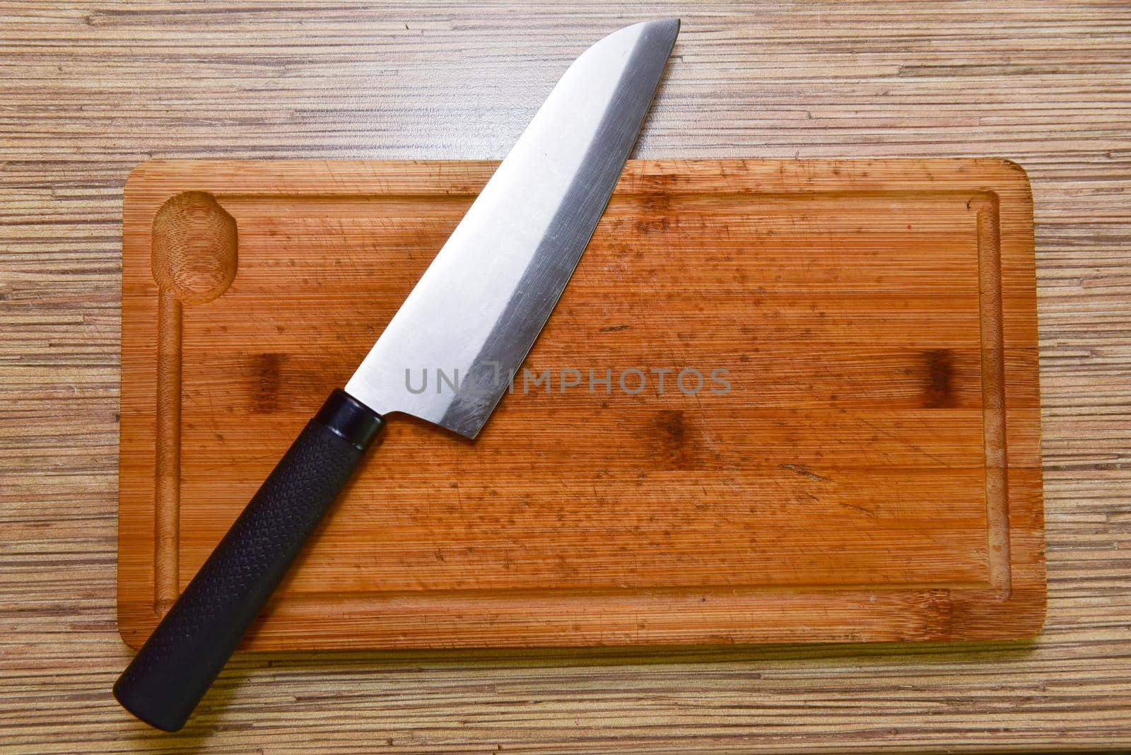 Cutting board and a kitchen knife on wooden background. Top view.