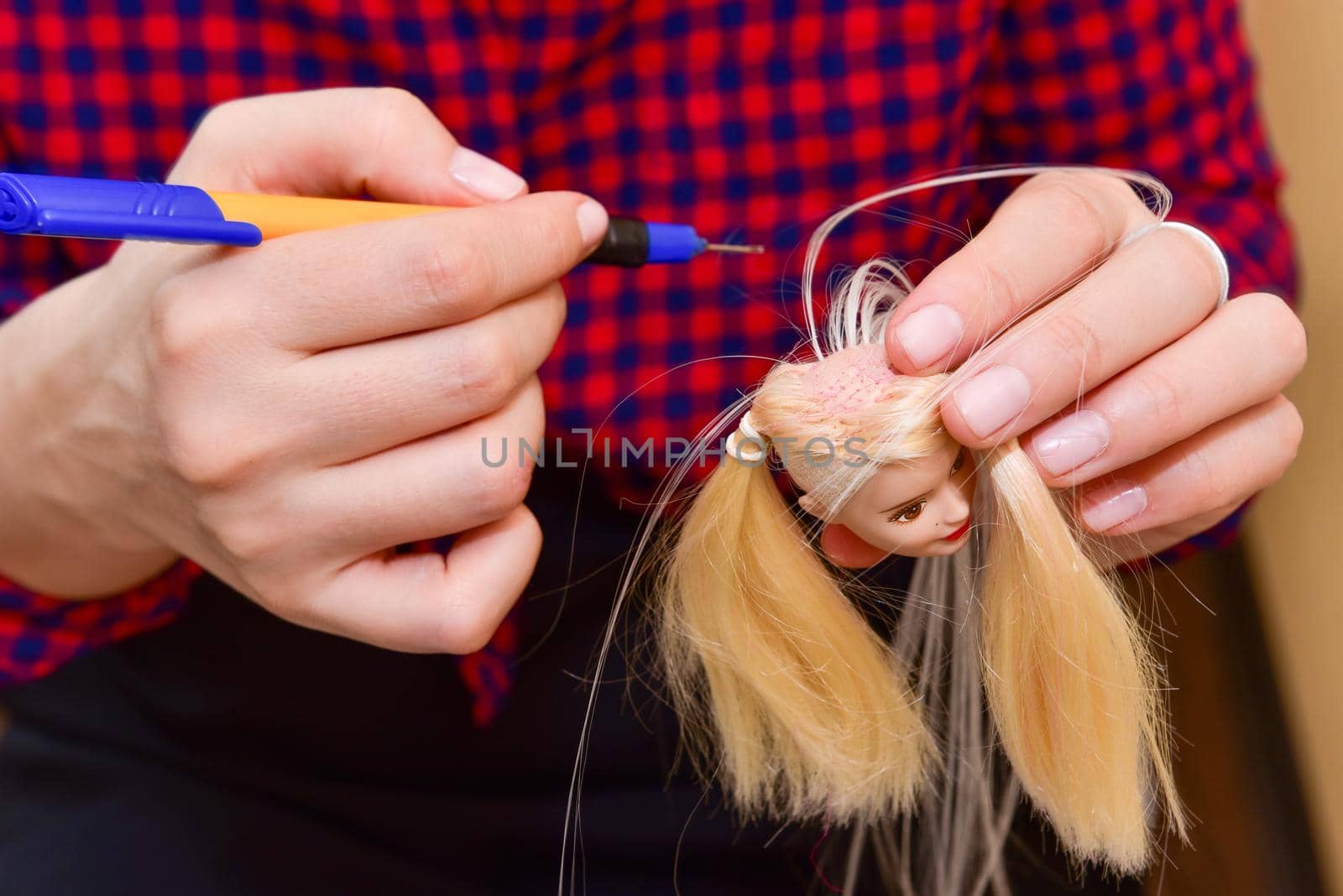 female hands and homemade tool, how to make a hairstyle for a doll, hobby concept.