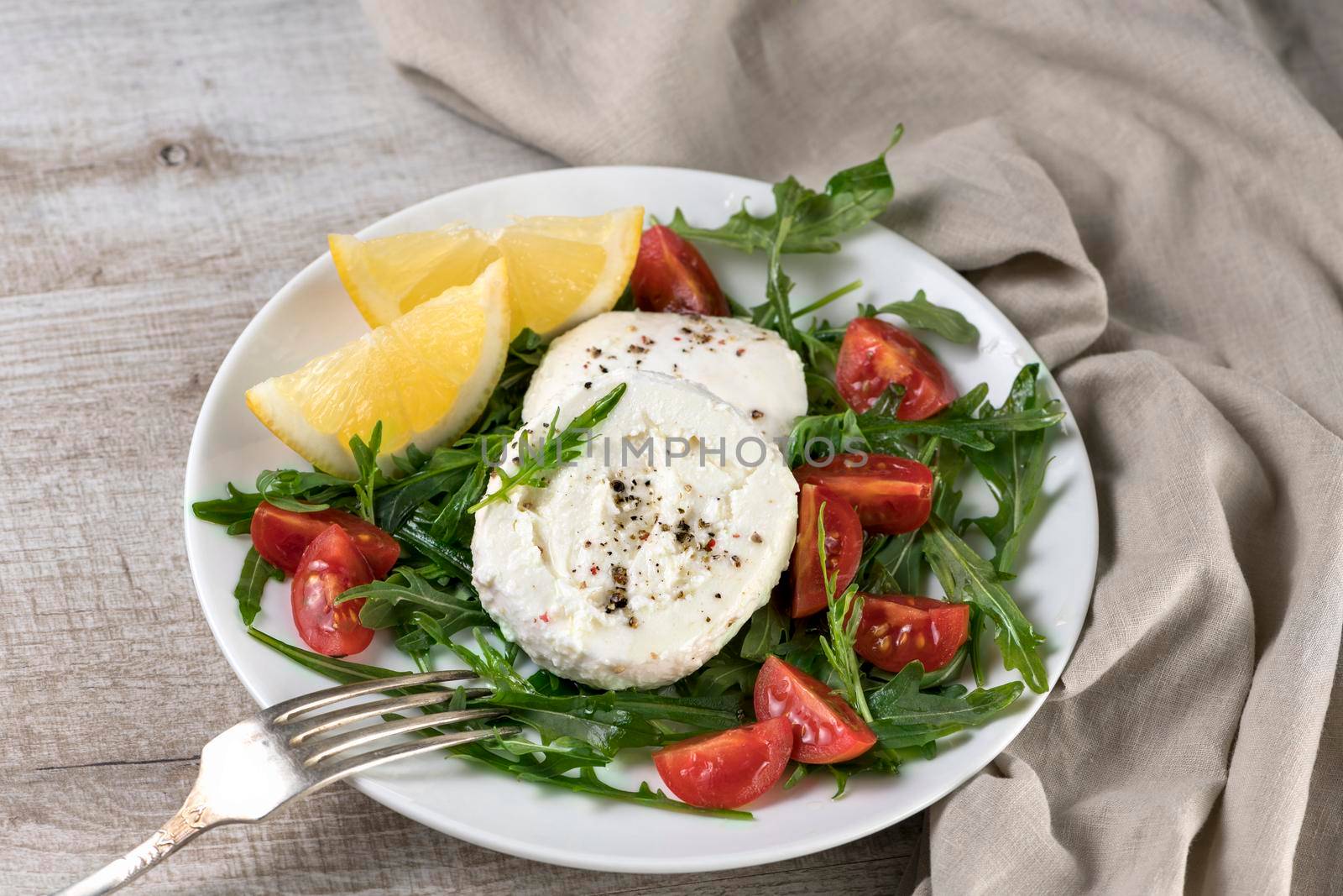 Mozzarella salad with arugula, cherry tomatoes, lemon, seasoned with spices and olive oil