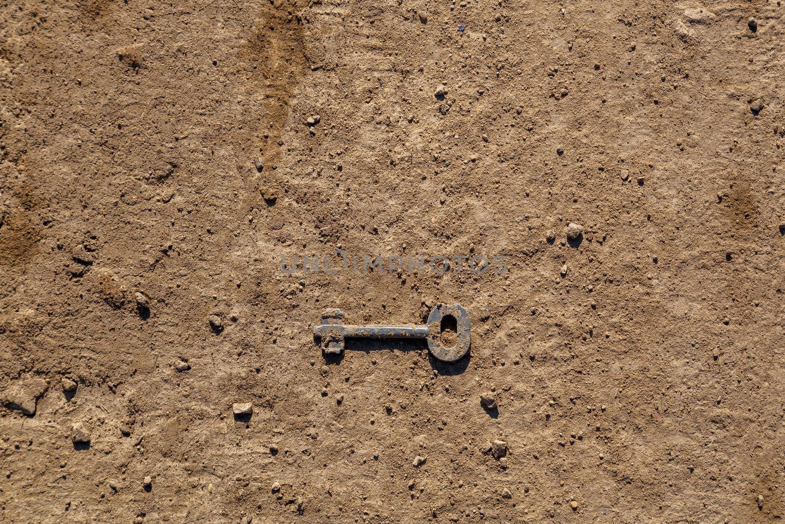 old key on dry dirt ground surface under direct sunlight.