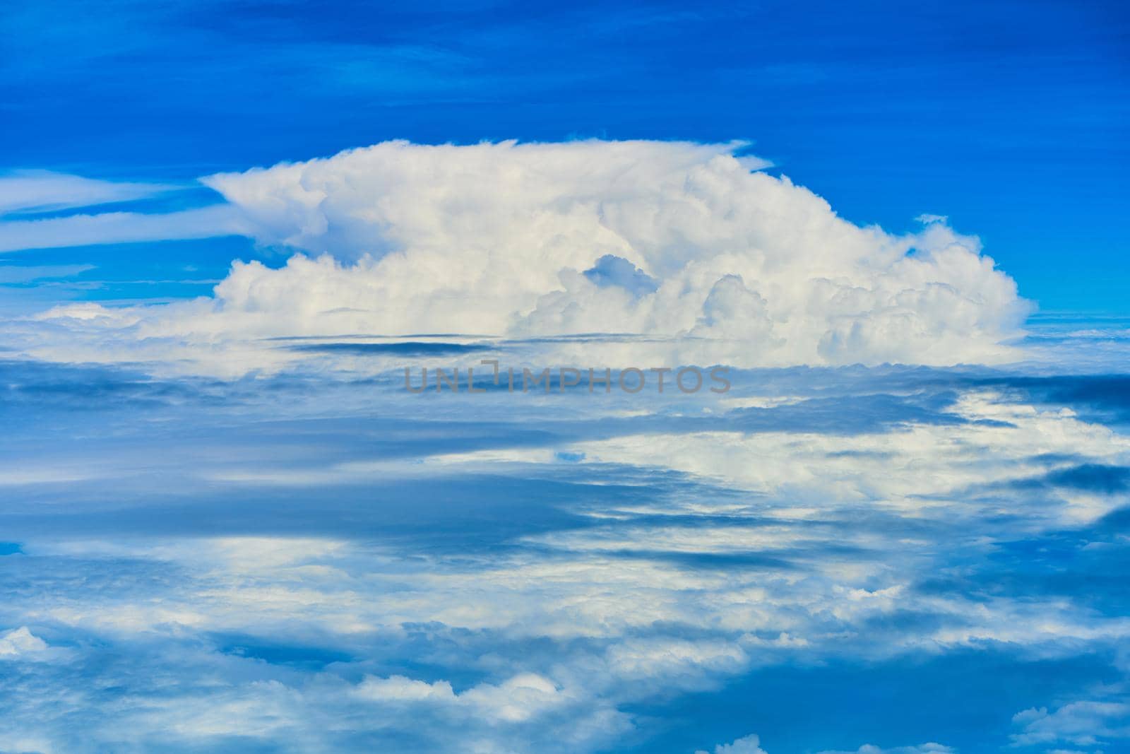 Landscape of fluffy white clouds on a dark blue sky. View from the plane at high altitude.
