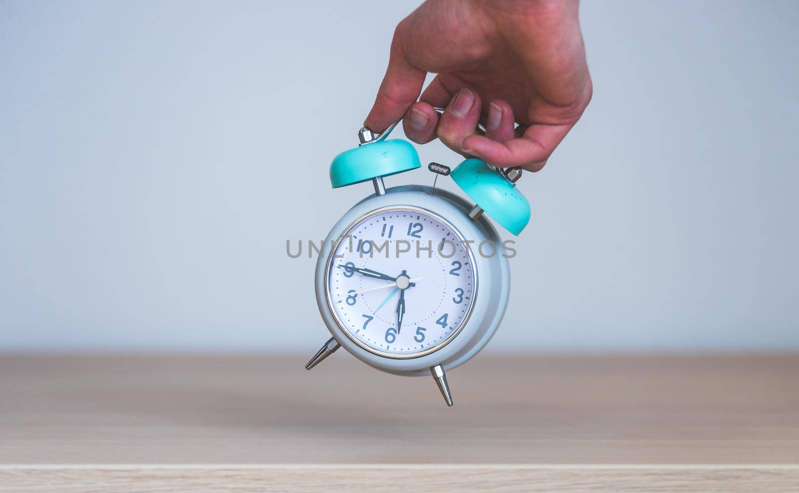 Male hand is holding a retro styled white alarm clock, isolated