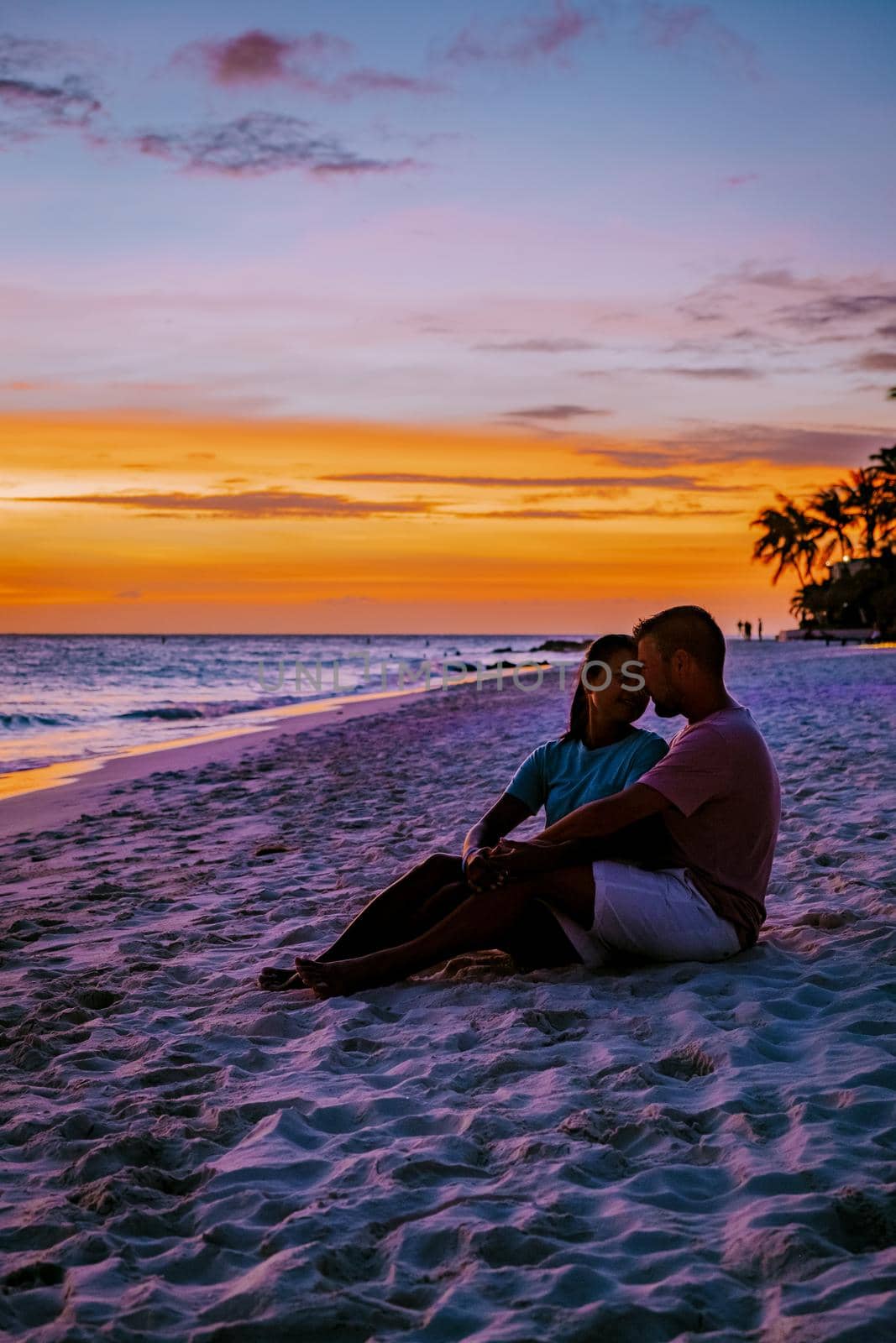 Sunset at Eagle Beach Aruba, Divi Dive Trees on the shoreline of Eagle Beach in Aruba, couple man and woman watchin sunset on the beach of Aruba