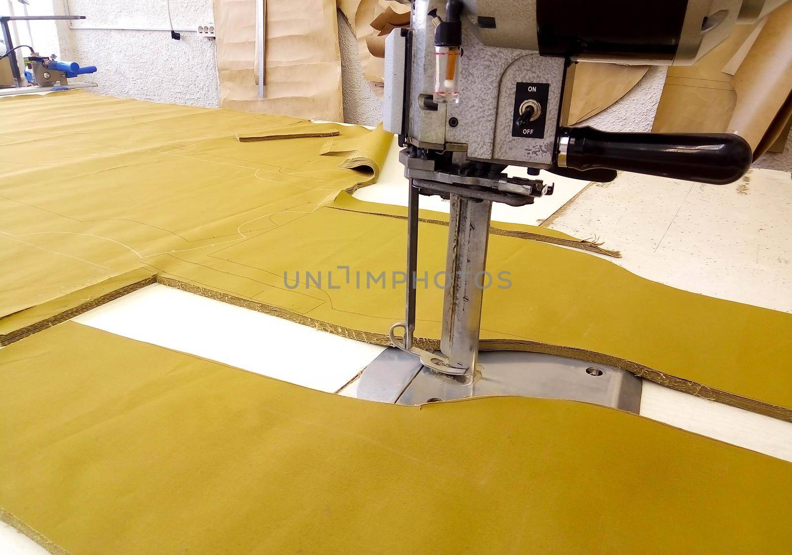Tool cutter in the garment industry. Cutting parts of clothing with an electric knife made of multi-layer fabric.
