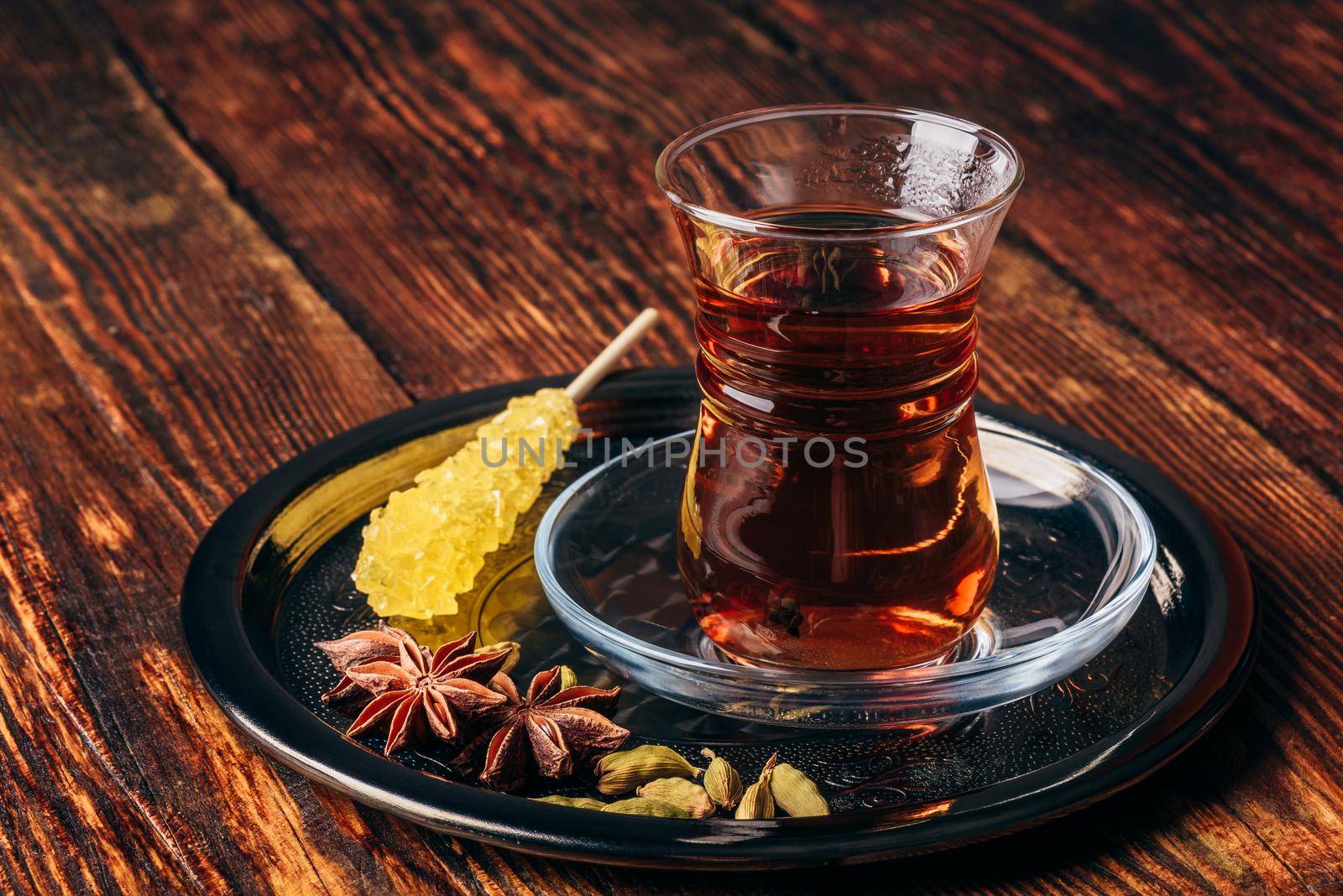 Oriental glass with Spiced tea and navad on metal tray over wooden surface