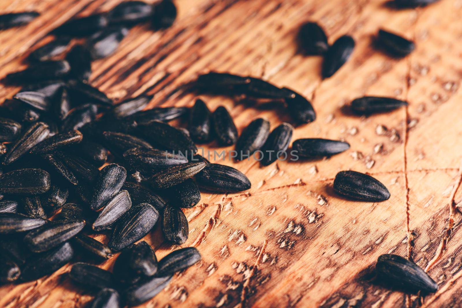 Scattered roasted sunflower seeds over wooden surface